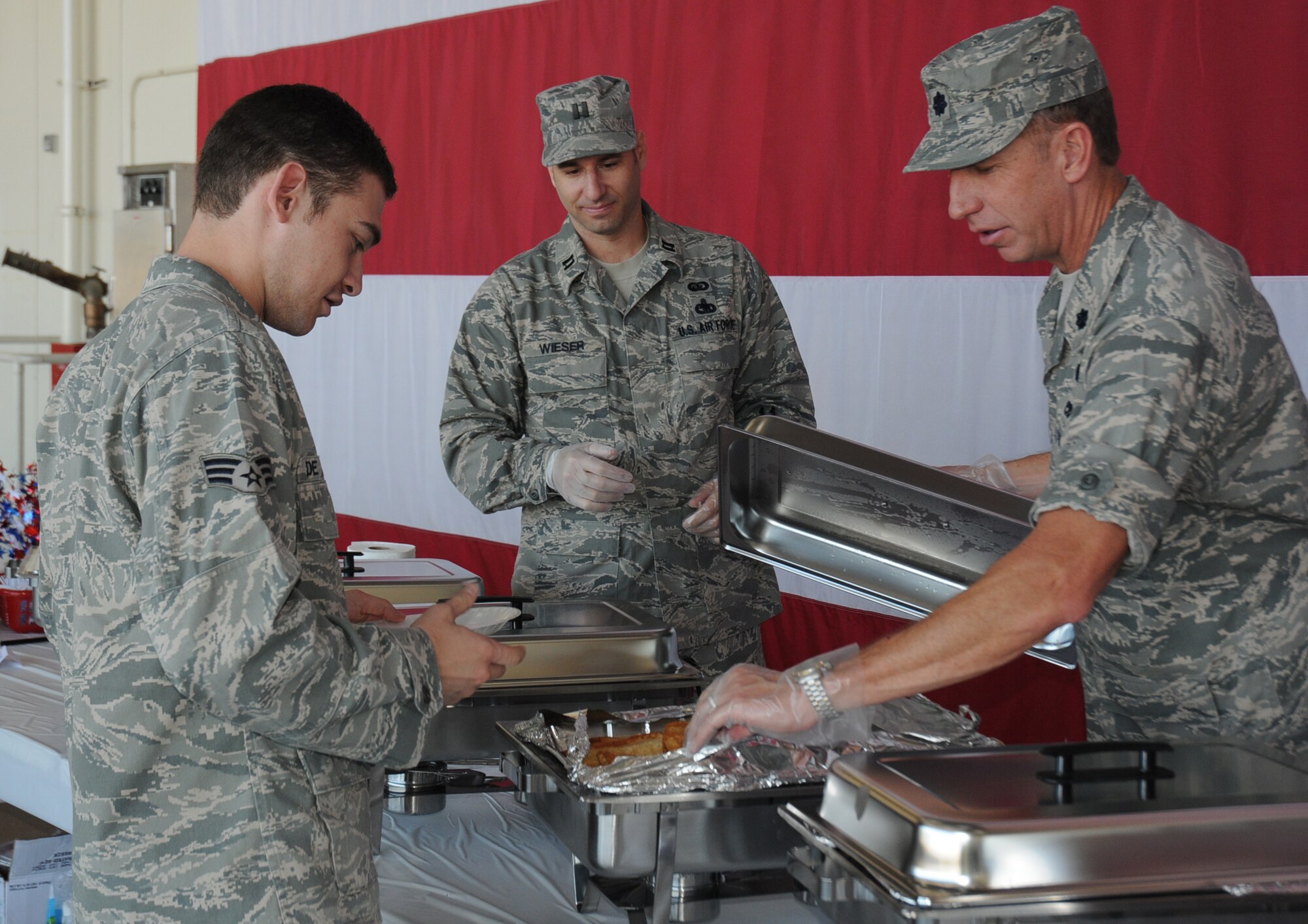 Capt. Philip Wieser, 944th Services Flight commander, watches as Lt. Col. Paul Theisen, 944th Mission Support Group commander, serves Senior Airman Zachary De Jesus, 944th Security Forces Squadron member, a sausauge and egg burrito during the wing's breakfast for the 944th Fighter Wing personnel on June 6. (U.S. Air Force Photo/Staff Sgt. Denise Willhite)