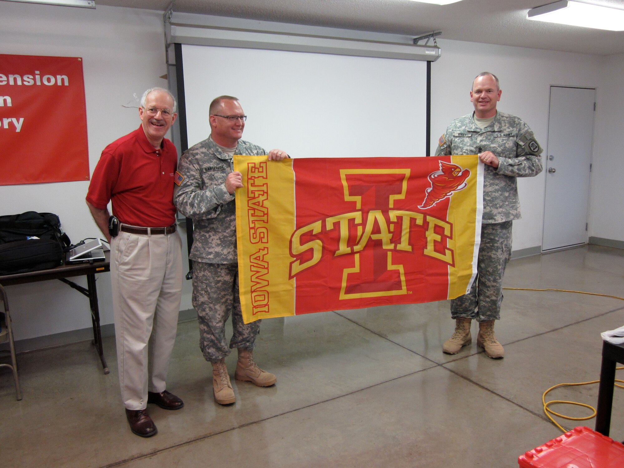 Dr. Gerald Miller, Iowa State University (ISU) Interim Vice President for Extension, presents COL Craig Bargfrede, 734th Agri-Business Development Team (ADT) Commander, and SGM Robert Reedy, 734th ADT Command Sergeant Major, with an ISU flag at the conclusion of ISU-ADT agricultural training.