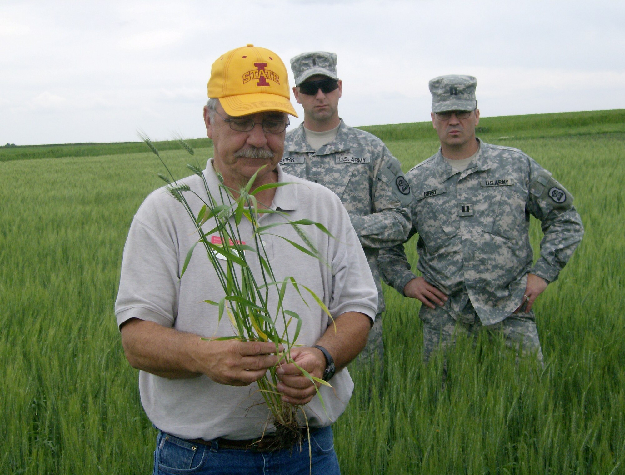1LT Scott Shirk and CPT Patrick Birgy of the 734th Agri-Business Development Team (ADT) observe Iowa State University (ISU) Extension wheat specialist Dr. Mark Carlton examine a wheat plant for disease during ISU-ADT agriculture training.