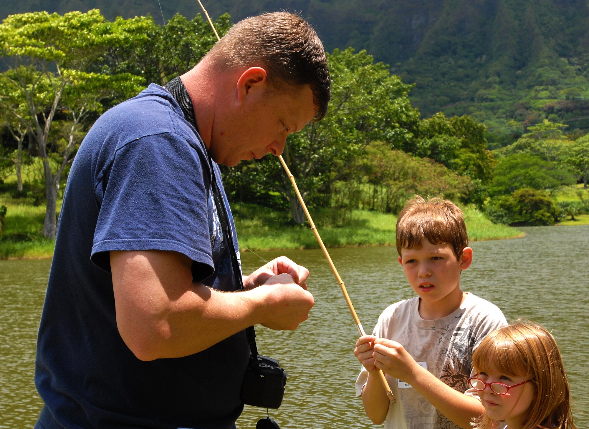 JOINT BASE PERAL HARBOR HICKAM, Hawaii -- Master Sgt. Mike Hammond, Pacific Air Forces staff, baits a barbless hook with bread for two of his children during the Keiki Fishing Tournament, hosted by Friends of Hickam, June 2 at the Ho`omaluhia Botanical Gardens. Keiki, the Hawaiian word for children, caught a tournament record 732 fish. This is the 11th straight year the Friends of Hickam has hosted the event for more than 200 children every year. (U.S. Air Force photo/SSgt. Mike Meares)
