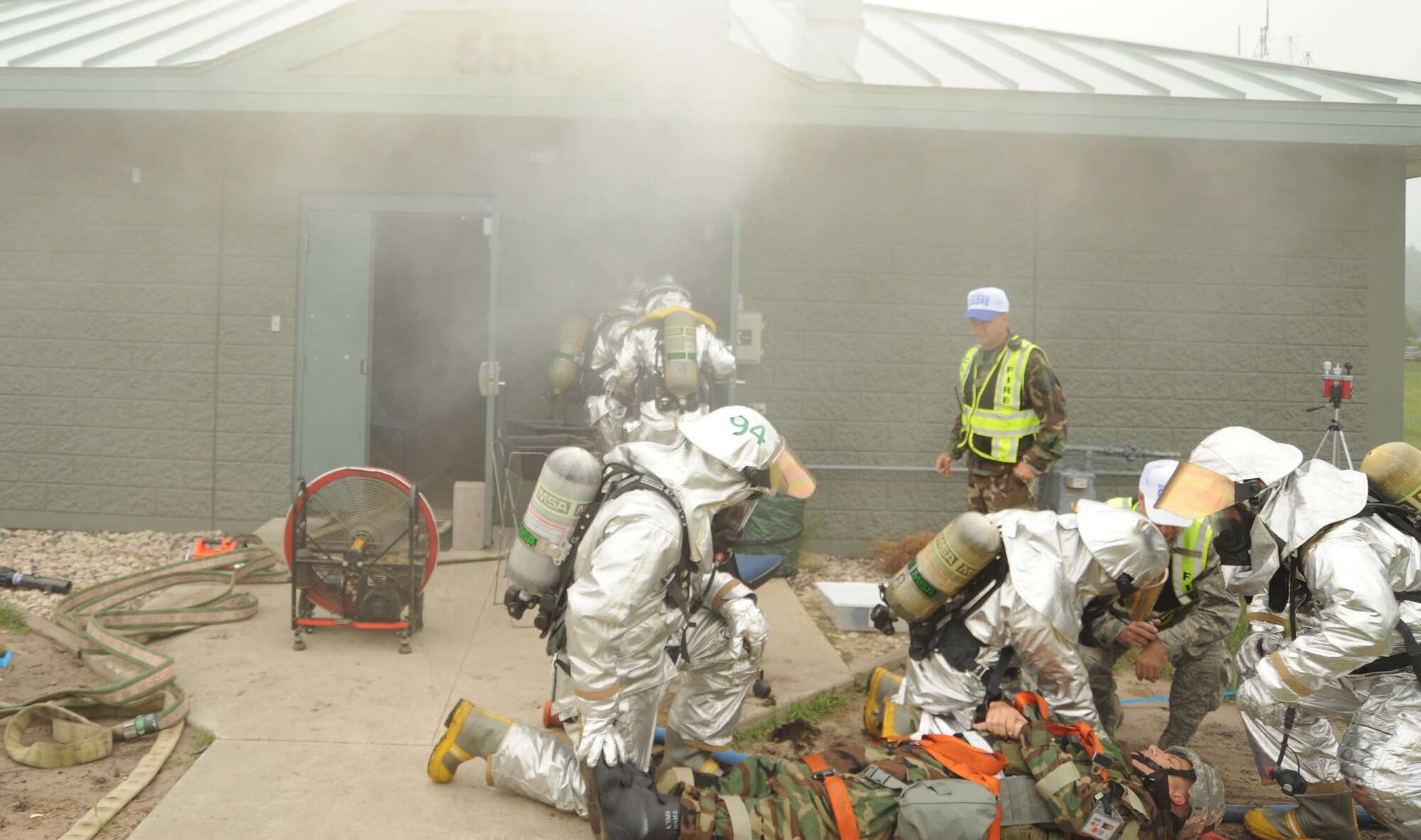 As smoke bellowed out the the command center, firefighters cleared the building of injured Airmen. The realistic scene was part of the "bugout" procedure for the ECT and command staff. Once the building was cleared, the firefighters started ventilating the rooms. It was later  discovered  faulty wiring in the air conditioner caused the smoke and subsequent evacuation. (Air Force photo by Jerry Green)