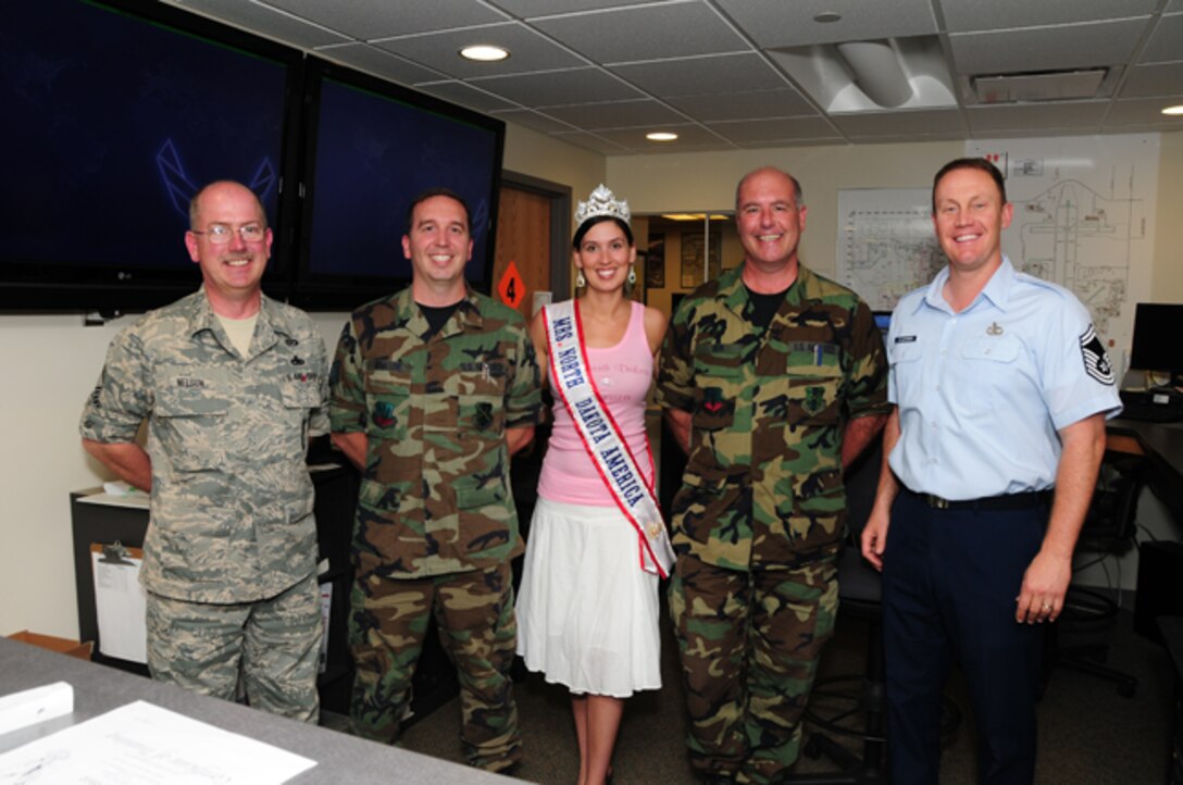 Newly crowned Mrs. North Dakota America, Tech. Sgt. Tera Miller, of the 119th Operations Support Squadron, visits her work area June 7, at the North Dakota Air National Guard, Fargo, N.D.  She is surrounded by her coworkers from left to right, Senior Master Sgt. Kevin Nelson, Tech. Sgt. Christopher Schatzke, Master Sgt. Brian Rook, and Senior Master Sgt. Scott Flickinger.  Miller was selected 2010 Mrs. North Dakota America at the Grand Masonic Lodge, June 6, in Fargo.  One of Millers competitors for the crown was fellow Guard member SGT. Jill Johnson, with the North Dakota Army National Guard.  Miller will advance to the national Mrs. America pageant in Tuscan, Ariz., in September. Miller, along with her twin sister Tech. Sgt. Lisa Narum joined the North Dakota Air National Guard in 2001. (DoD photo by Senior Master Sgt. David H. Lipp) 

