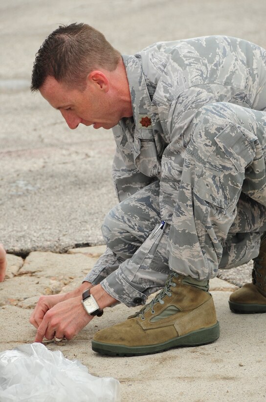 ELLSWORTH AIR FORCE BASE, S.D. -- Major Robert Kelly, 28th Communications Squadron commander, picks up rocks and debris during a foreign object debris walk, June 7.  The FOD walk helps ensure the flightline is safe and free of potentially hazardous debris which could cause millions of dollars worth of damage to a jet. (U.S. Air Force photo/Airman 1st Class Anthony Sanchelli)
