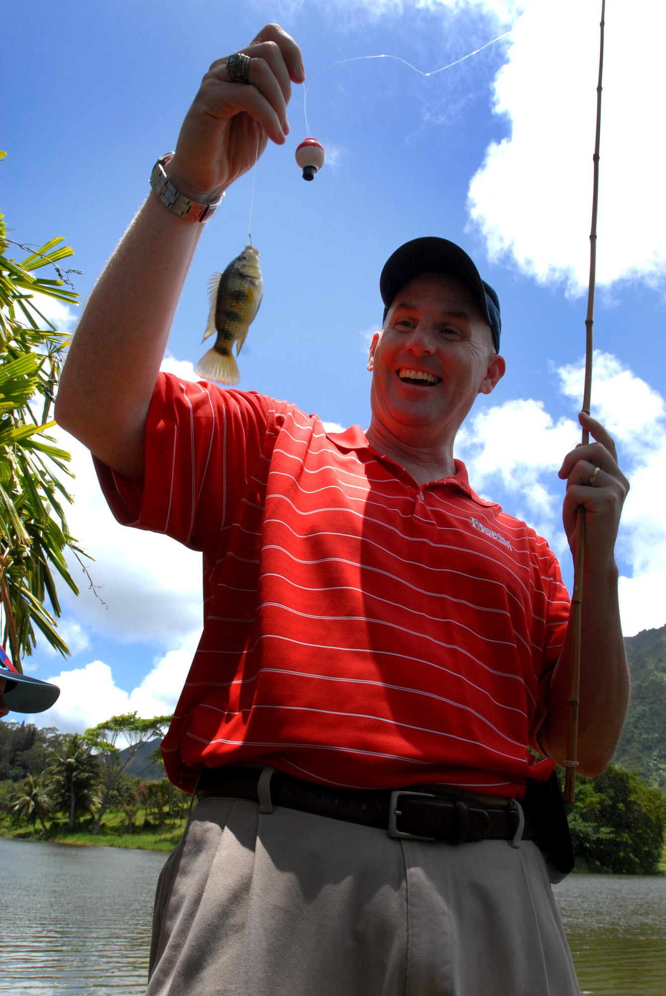 JOINT BASE PERAL HARBOR HICKAM, Hawaii  -- Col. Sam. Barrett, 15th Wing commander, admires the first catch of the day during the Friends of Hickam Keiki Fishing Tournament June 2 at the Ho`omaluhia Botanical Gardens. Keiki, the Hawaiian word for children, caught 732 fish at the fishing tournament. This is the 11th straight year the Friends of Hickam has hosted the event for more than 200 children. (U.S. Air Force photo/SSgt. Mike Meares)