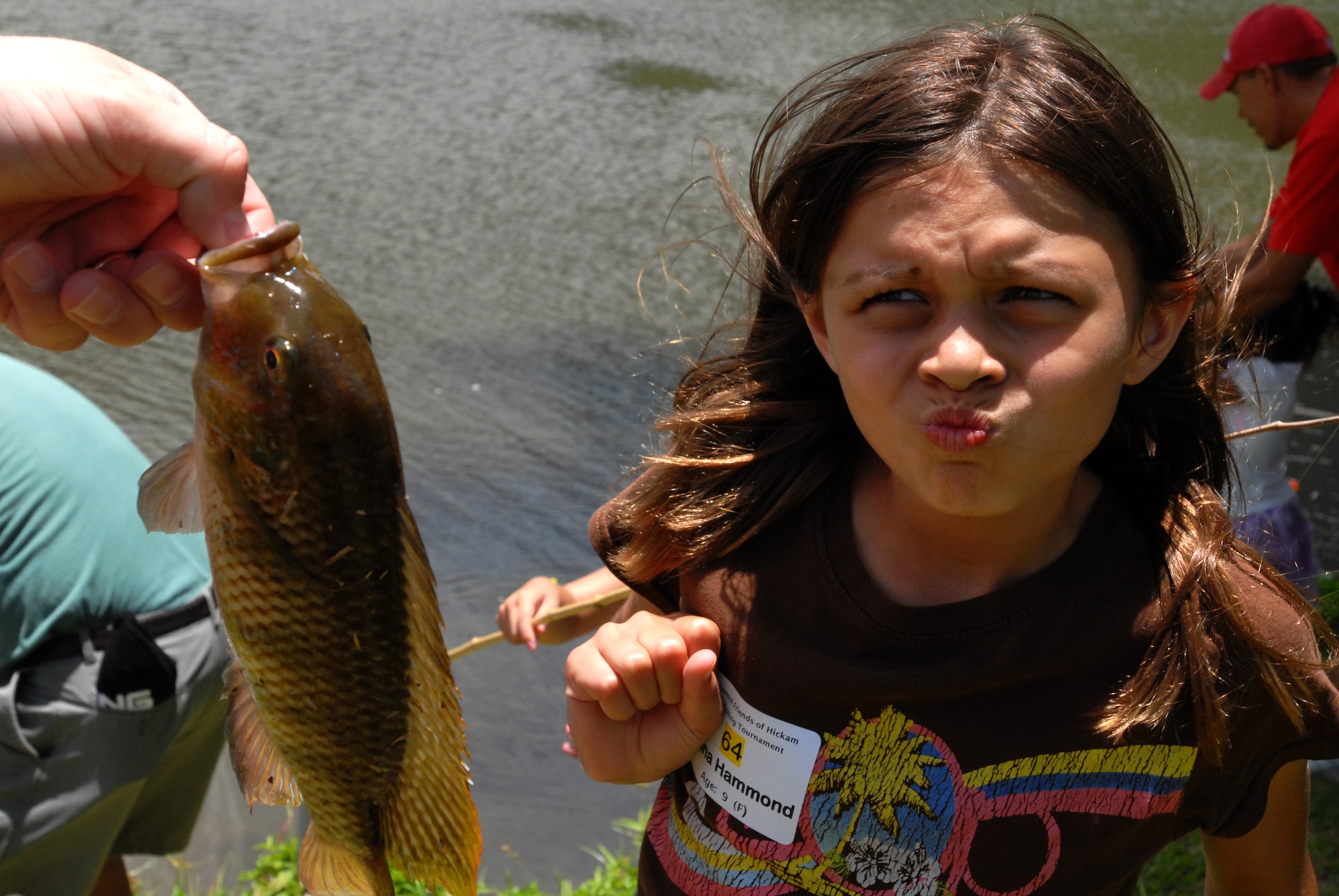 JOINT BASE PERAL HARBOR HICKAM, Hawaii  -- Jenna Hammond, 9, takes a look at the "slimy" fish she just caught as her dad, Master Sgt. Mike Hammond, Pacific Air Forces staff, holds it for her during the Keiki Fishing Tournament, hosted by Friends of Hickam, June 2 at the Ho`omaluhia Botanical Gardens. Keiki, the Hawaiian word for children, caught a tournament record 732 fish. This is the 11th straight year the Friends of Hickam has hosted the event for more than 200 children every year. (U.S. Air Force photo/SSgt. Mike Meares)