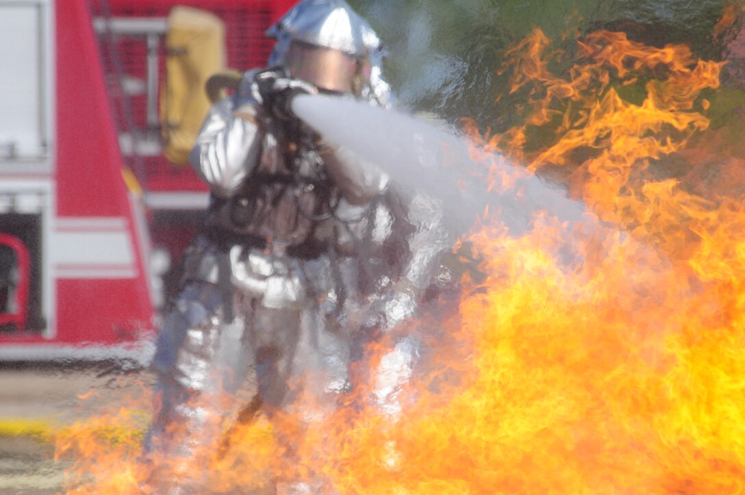 Master Sgt. Bruce Bauske leads Staff Sgt. Jon Lague, both of the 119th Civil Engineer Squadron, on a two-person hose team June 4, as they approach a mock aircraft burn pit while performing fire fighter training at the North Dakota Air National Guard Regional Training Site, Fargo, N.D.  The mock aircraft burn pit provides realistic training for the fire fighters with technically controled flames eminating from various areas of a metal airplane frame.