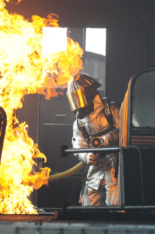 Senior Airman Alan Negron, of the 119th Civil Engineer Squadron, prepares to fight a fire in the interior of a mock aircraft June 5, while performing fire fighter training at the North Dakota Air National Guard Regional Training Site, Fargo, N.D.  The mock aircraft burn pit provides realistic training for the fire fighters with technically controlled flames emanating from various areas of a metal airplane frame.