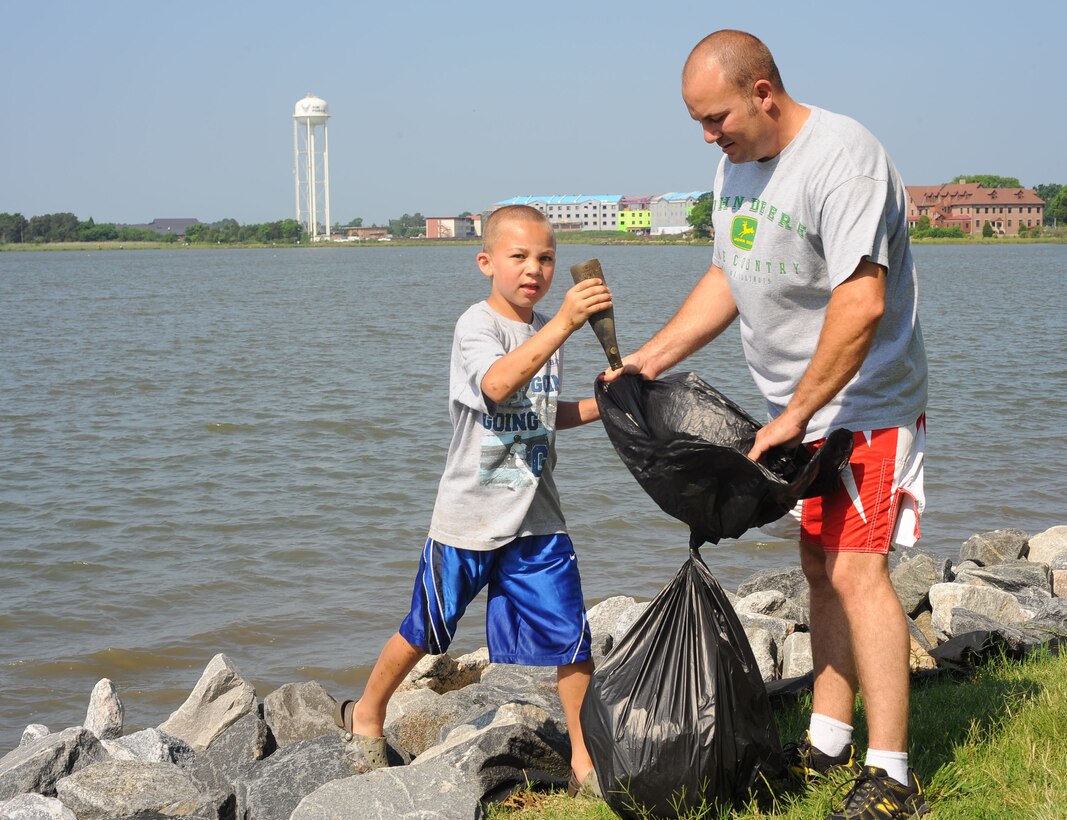 LANGLEY AIR FORCE BASE, Va. – Tech. Sgt. Justin McDougal, 1st Maintenance Operations Squadron Maintenance Operations Center controller, collets a bottle from his son, Austin, 8, during Langley's annual Clean the Bay Day June 5.  Volunteers collected more than 8,000 pounds of trash during the three-hour clean-up.  (U.S. Air Force photo/Staff Sgt. Barry Loo)