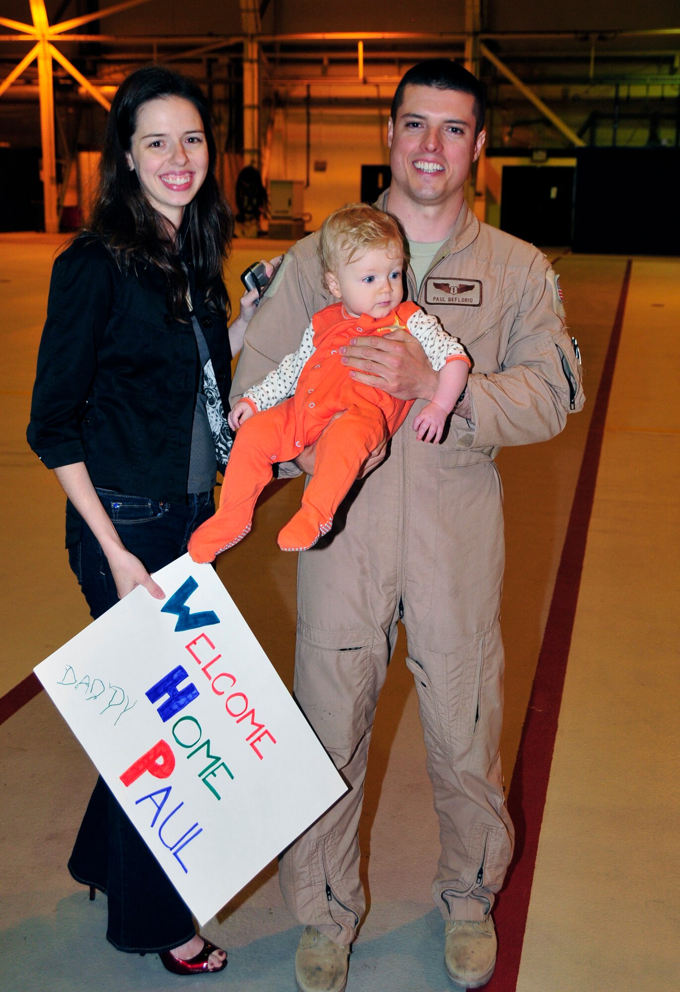 Maj. Paul DeFlorio, 56th Rescue Squadron flight doctor, holds his son, Wyatt, for the first time in three months with his wife Amanda at Hangar 7 at RAF Lakenheath, England, June 7. During their recent 90-day deployment to Bagram Air Base, Afghanistan completed more than 495 combat hours in support of Operation Enduring Freedom. (U.S. Air Force photo/Airman 1st Class Eboni Knox)