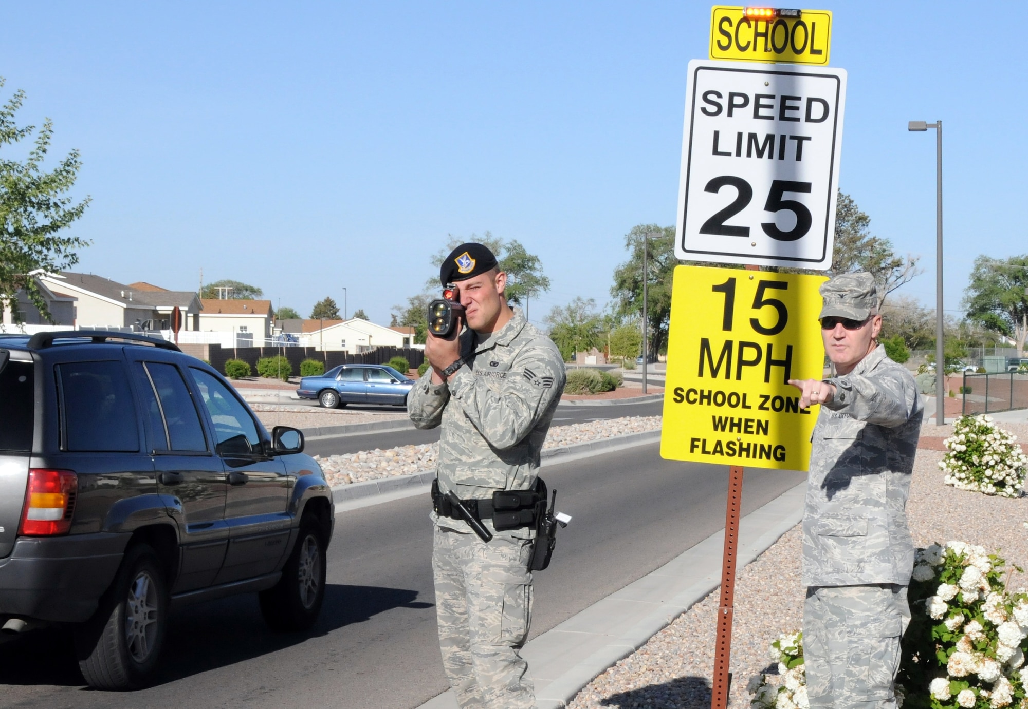 Col. Matthew Bartlett, 377 MSG commander observes the traffic coming from the housing area into the Sandia Elementary School zone while Senior Airman Charlie Cornacchio, 377 SFS operates the radar gun on May 11th. U. S. Air Force photo by Dennis Carlson