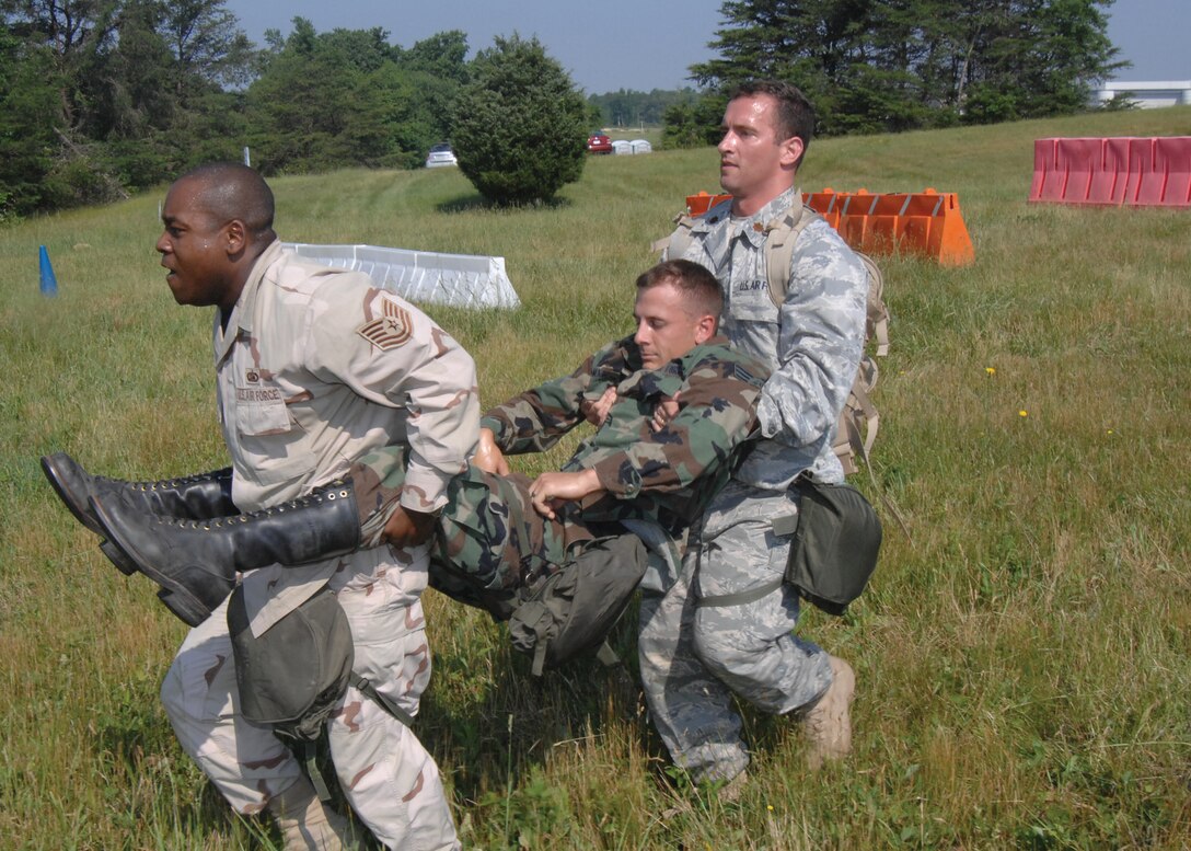 JOINT BASE ANDREWS, Md. -- Maj. Ryan Principi, 844th Communications Group, and Tech. Sgt. Derrick Mayo, 744th Communications Squadron, carry Airman 1st Class Michael Musiowski, 744 CS, simulating evacuating a wounded Airman as part of the “Warrior Day” here May 27. (U.S. Air Force photo by Staff Sgt. Christopher Marasky) 
