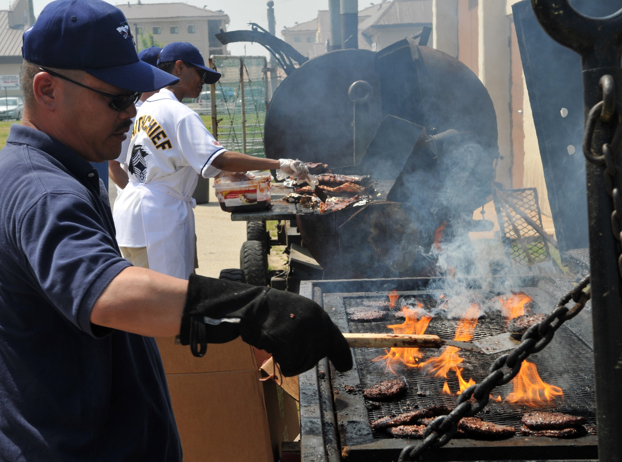 Chief Master Sgt. Ricky Hamada, 8th Maintenance Group, and Chief Master Sgt. Kim Baker, 8th Logistics Readiness Squadron, prepare hamburgers, brats, ribs and drinks for attendees May 21 during the 8th Fighter Wing Junior Enlisted Appreciation Day. The Kunsan Top III Association sponsored the day of music, sports, food and fun as a way to thank junior enlisted Airmen and Soldiers for the hard work they do every day to accomplish the wing's mission. (U.S. Air Force photo/Capt. Shannon Collins)