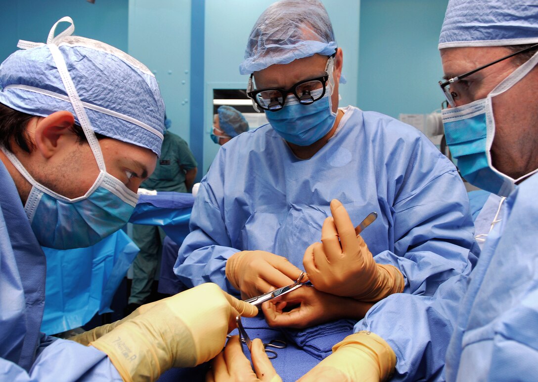 Adrian Diaz, left, a member from the University of San Diego Pre-Dental Society, cuts the stitching line as U.S. Navy Cmdr. (Dr.) Matthew T. Provencher, center, concludes the surgery of removing an extra thumb from a Vietnamese patient aboard the Military Sealift Command hospital ship USNS Mercy during a visit to Quy Nhon, Vietnam, supporting Pacific Partnership 2010, June 5, 2010.