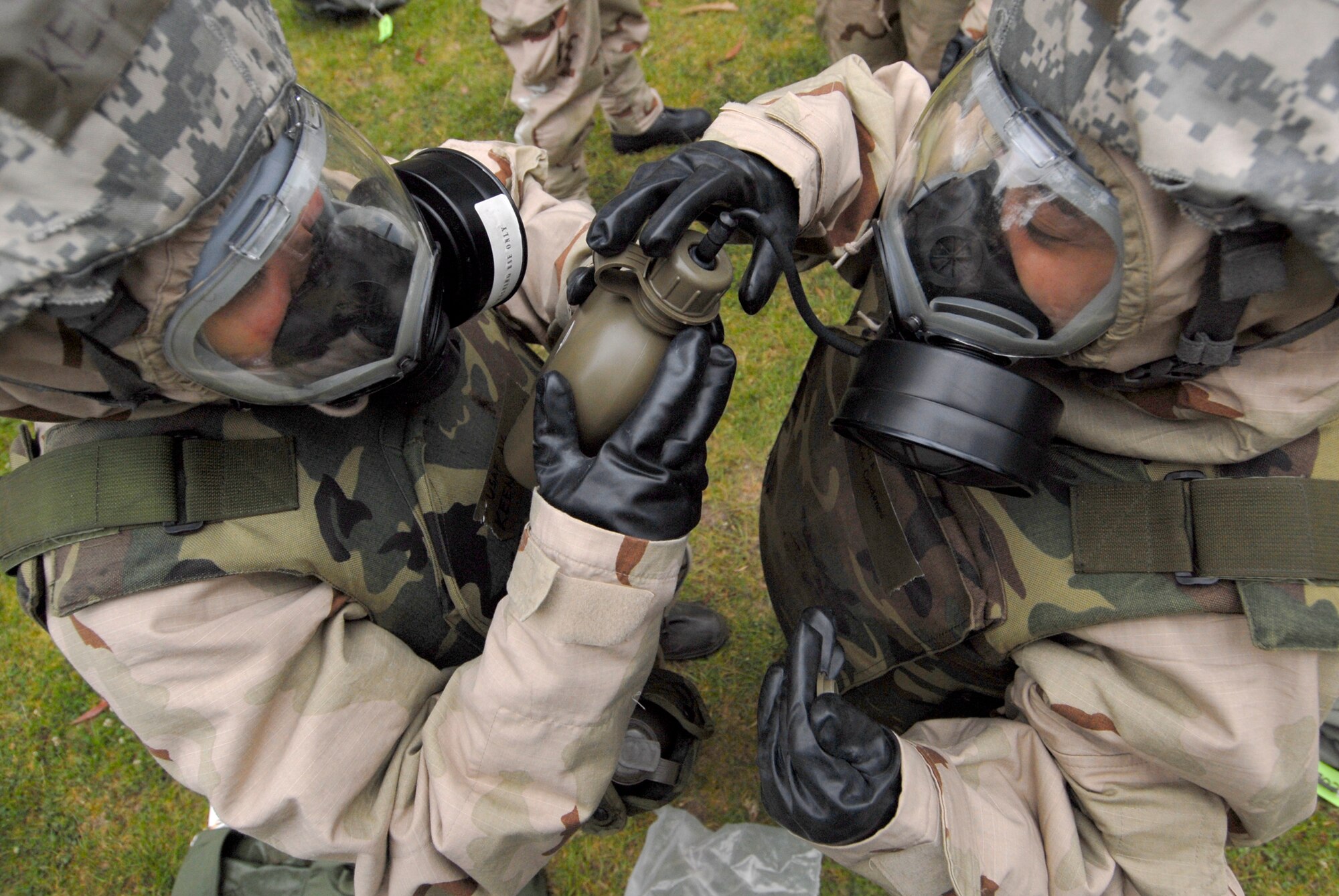 VANDENBERG AIR FORCE BASE, Calif. --  Airman 1st Class Keen Santiago and Senior Airman Jhordimae Cardenas, from the 30th Medical Support Squadron assist each other with attaching their drinking tubes to their Mission Oriented Protective Posture level masks during a North Star training course at Cocheo Park here Tuesday, June 8, 2010.  The course included MOPP four level preparation, self aid and buddy care and explosives ordnance awareness.  (U.S. Air Force photo/Senior Airman Andrew Satran) 

 
 




