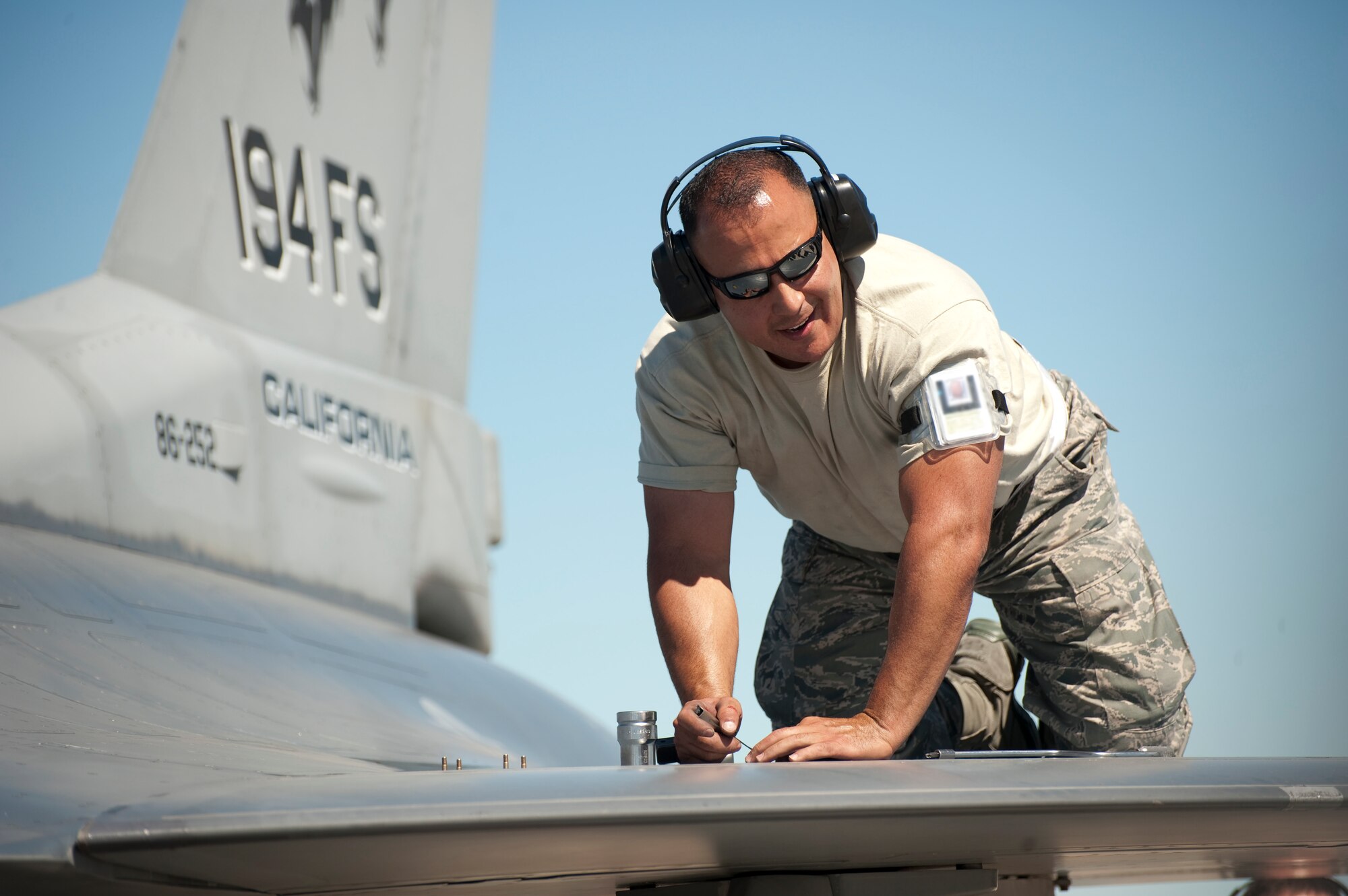 Ssgt Johnny Martinez of the 144th Fighter Wing communicates with his fellow airmen as he prepares to secure the external fuels tanks of the F-16 Falcon prior to its launch. The activities took place during Operation Coronet White as part of the 2010 Operational Readiness Inspection at the 144th Fighter Wing in Fresno, California from 04 June through 07 June 2010. (USAF photograph by Tsgt David J. Loeffler)