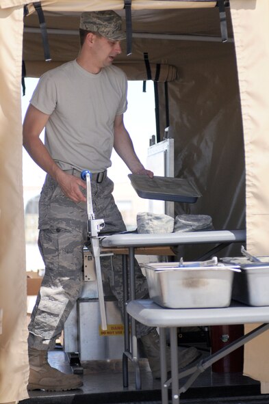 Staff Sgt. Jake Sulwer, prepares unitized group rations on the flightline at Tucson International Airport, June 5. Sulwer, and other members of the 162nd Services Flight, practiced using a Single Pallet Expeditionary Kitchen during a drill weekend here. (Air Force photo by Airman First Class Krystal Tomlin)