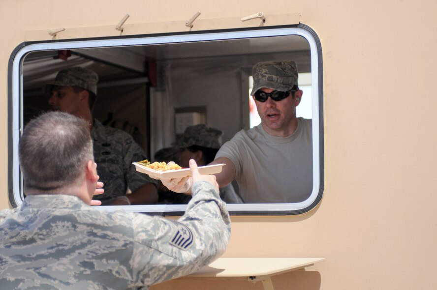Staff Sgt. Erich Smith, hands a hot meal to a fellow Arizona Air National Guardsman on the flightline at Tucson International Airport, June 5. Smith, and other members of the 162nd Services Flight, practiced using a Single Pallet Expeditionary Kitchen during a drill weekend here. (Air Force photo by Airman First Class Krystal Tomlin)
