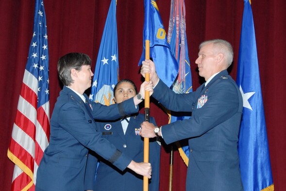 Brig. Gen. Terry Djuric (left), Holm Center commander, presents the Officer Training School flag to Col. Timothy P. O'Brien (right), the incoming OTS commandant, during the school's change of command ceremony as Master Sgt. Jacqueline Barfield, the school's superintendent, looks on. Colonel O'Brien is the first Air National Guard officer to lead OTS. (U.S. Air Force/Bennett Rock)