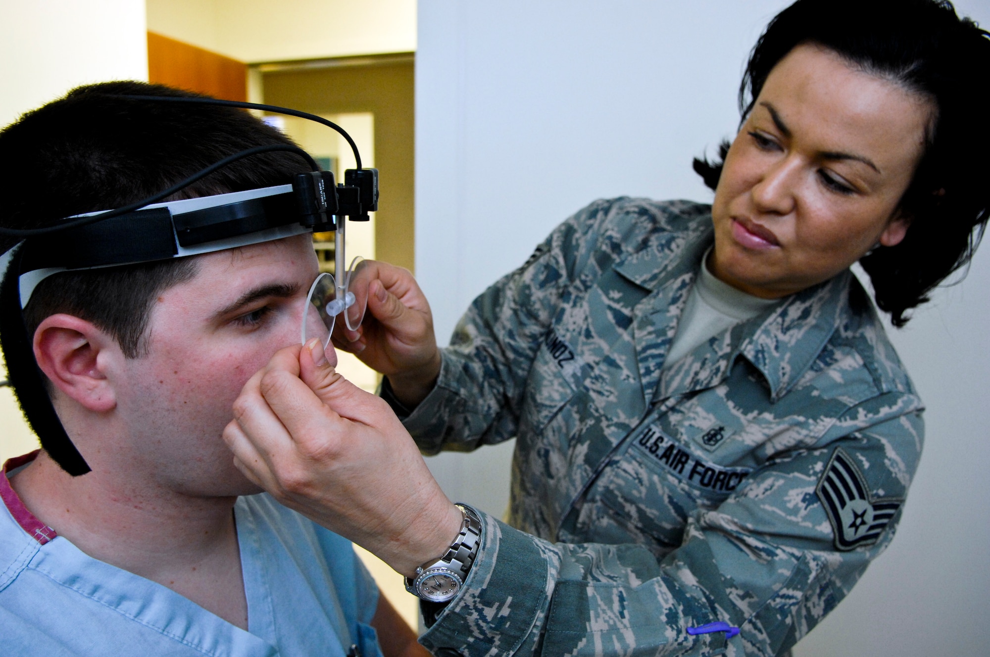 ELMENDORF AIR FORCE BASE, Alaska –Staff Sgt. Kim Munoz, 3rd Medical Group Otolaryngology technician adjusts a set of eye movement sensitive lenses on Airman 1st Class Matthew Kenneson, 3rd Medical Group surgical service technician. The lenses, along with a chair designed to spin, sit in a room made to test a patient’s equilibrium and balance. (Air Force photo by Airman 1st Class Jack Sanders)