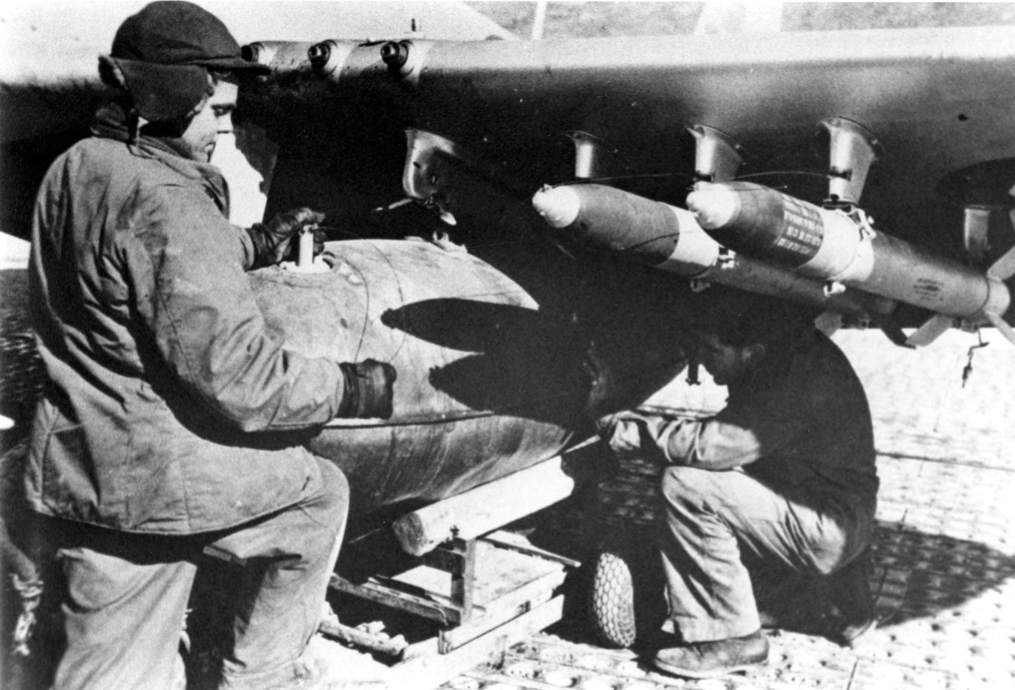 Armorers load a napalm bomb onto the wing of an F-51D. Napalm is a mixture of gasoline and a thickening agent which gives it the consistency of jelly. (U.S. Air Force photo)