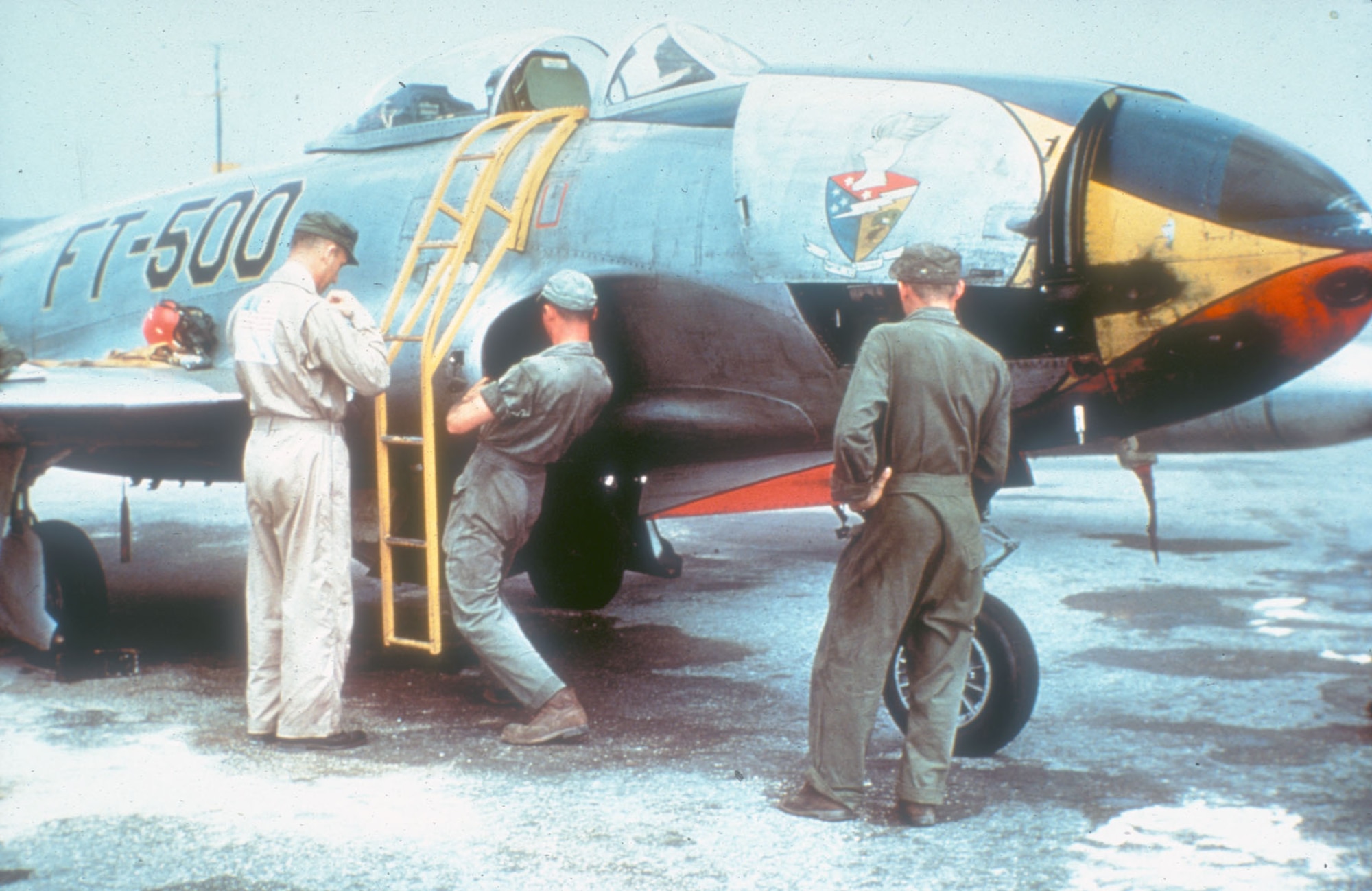 An F-80 pilot removes his flight gear as the ground crew checks the aircraft after a mission. (U.S. Air Force photo)