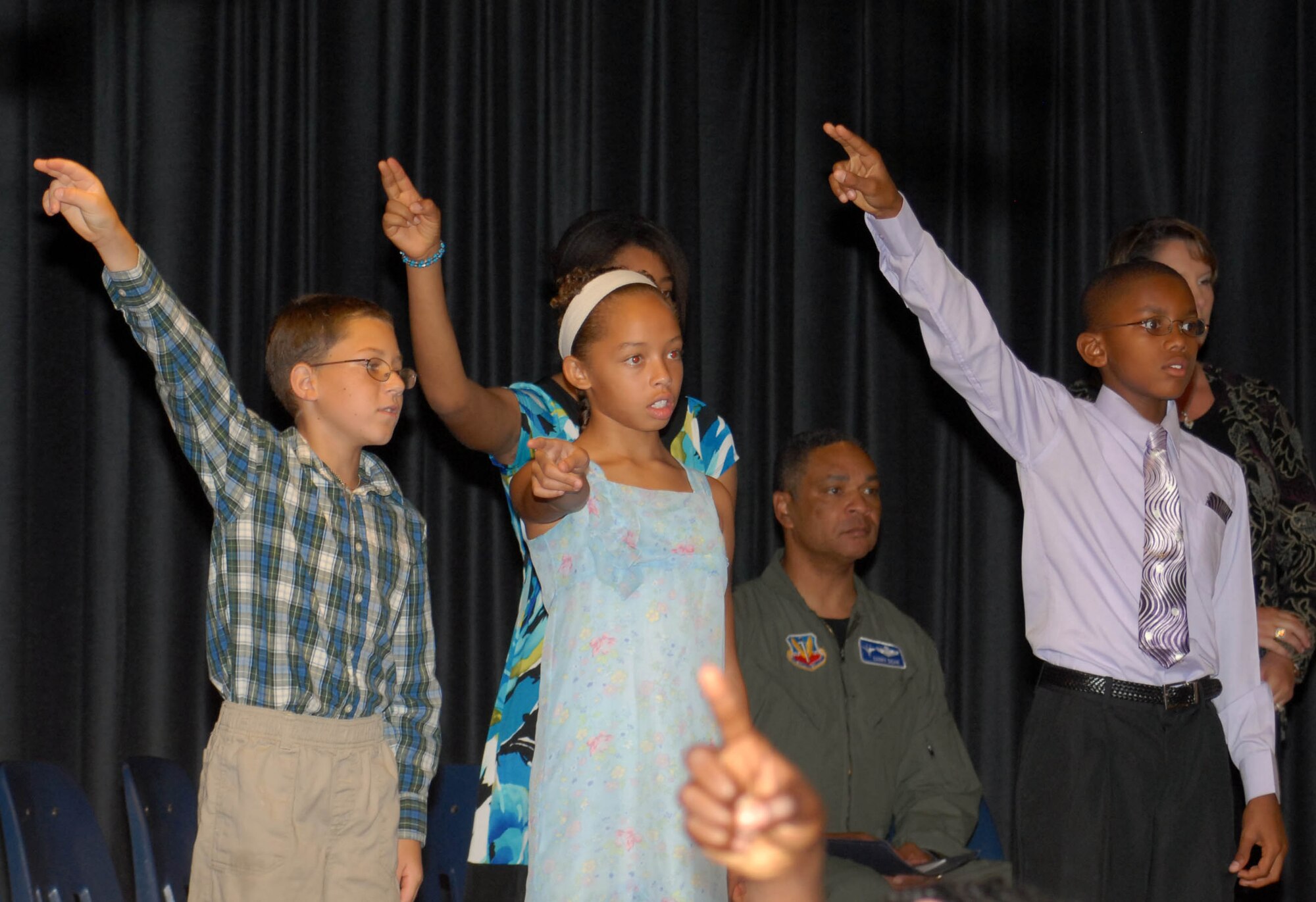 Fifth graders Brandon Oncale, Adora Walker, Ashley Kennedy and Diy’Quon Roulhac sing the Tyndall Thunderbird song during the school’s 5th Grade Recognition Ceremony June 4, 2010, where Maj. Gen. Garry C. Dean (pictured rear) delivered the ceremony’s keynote speech.  “Continue to strive for excellence and take advantage of every opportunity,” General Dean told the students.
