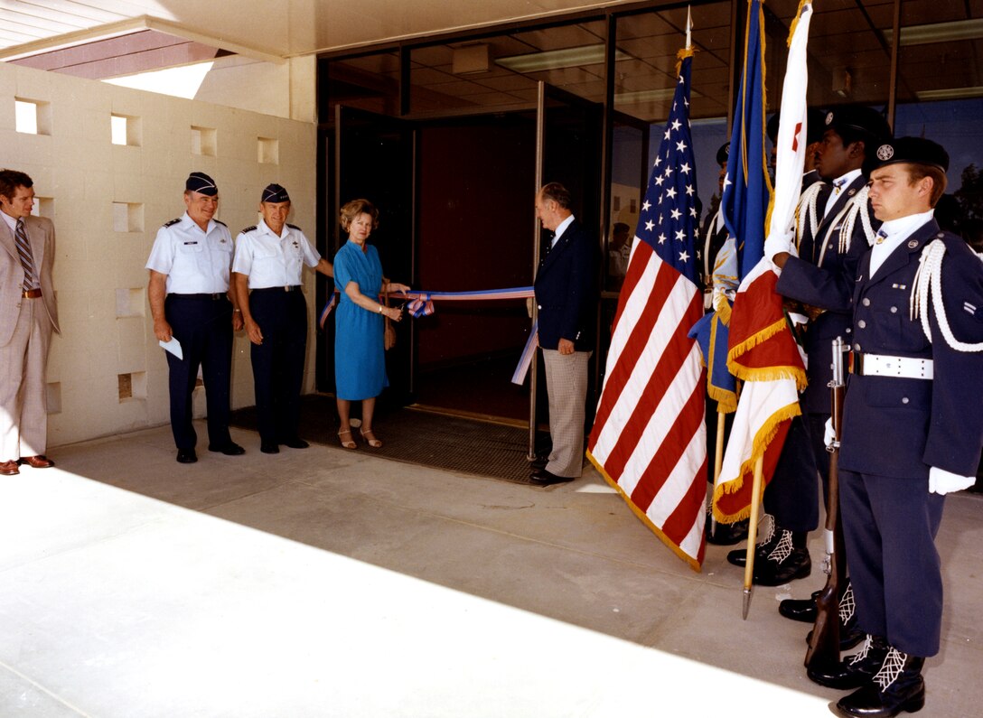 Col. Jackie L. Ridley 's widow, Mrs. Nell Ridley Loe, and retired Brig. Gen. Chuck Yeager (right of the door) cut the ceremonial ribbon to the Ridley Mission Control Center, June 12, 1980.  General Yeager, who flew with Colonel Ridley and was a close friend, said supersonic flight may not have been achieved without Colonel Ridley's analysis and intellect. (Official Air Force photo)