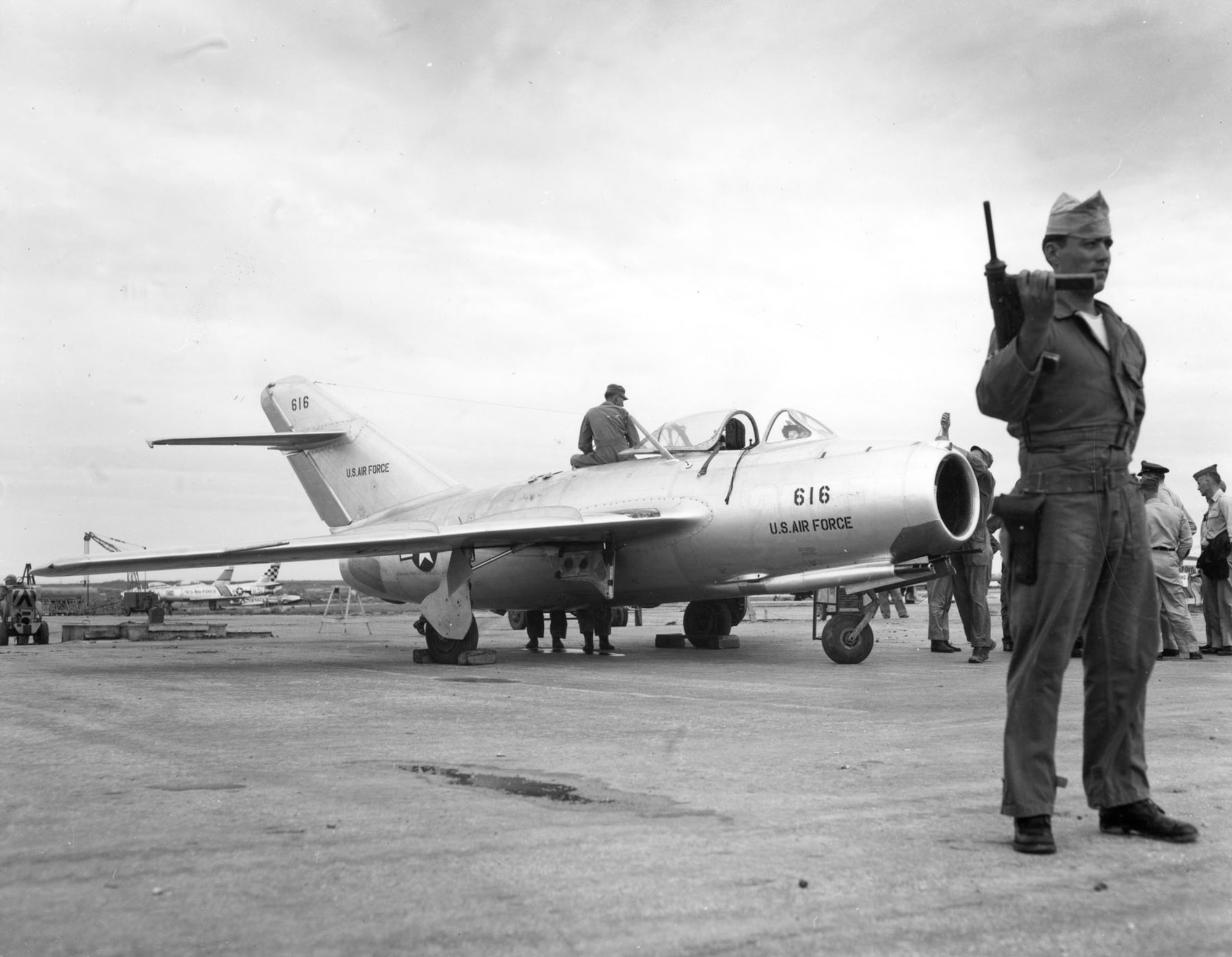 Repainted in USAF markings and insignia, the MiG-15bis under guard and awaiting flight-testing at Okinawa. (U.S. Air Force photo)