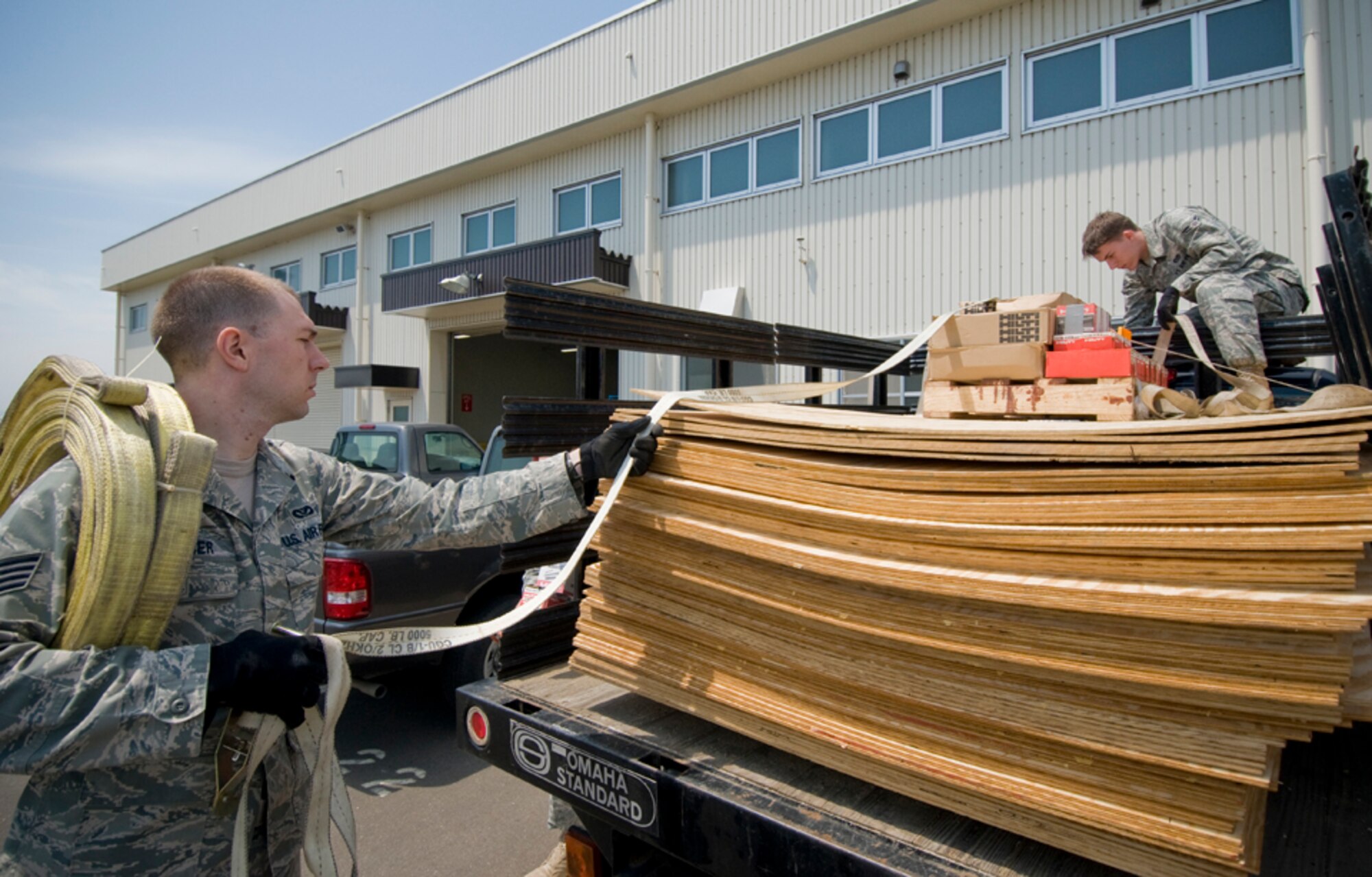 MISAWA AIR BASE, Japan -- Staff Sgt. Leslie Weidner and Airman 1st Class James Adams, 35th Civil Engineer Structures Flight structure technicians, unload plywood from a truck at the structure’s work center, June 3. Airmen and Japanese nationals from the 35th CES structures shop are routinely tasked to work on floors, footings, walls, doors, windows and components of prefabricated and permanent structures across the base. (U.S. Air Force photo/Senior Airman Jessica Lockoski)