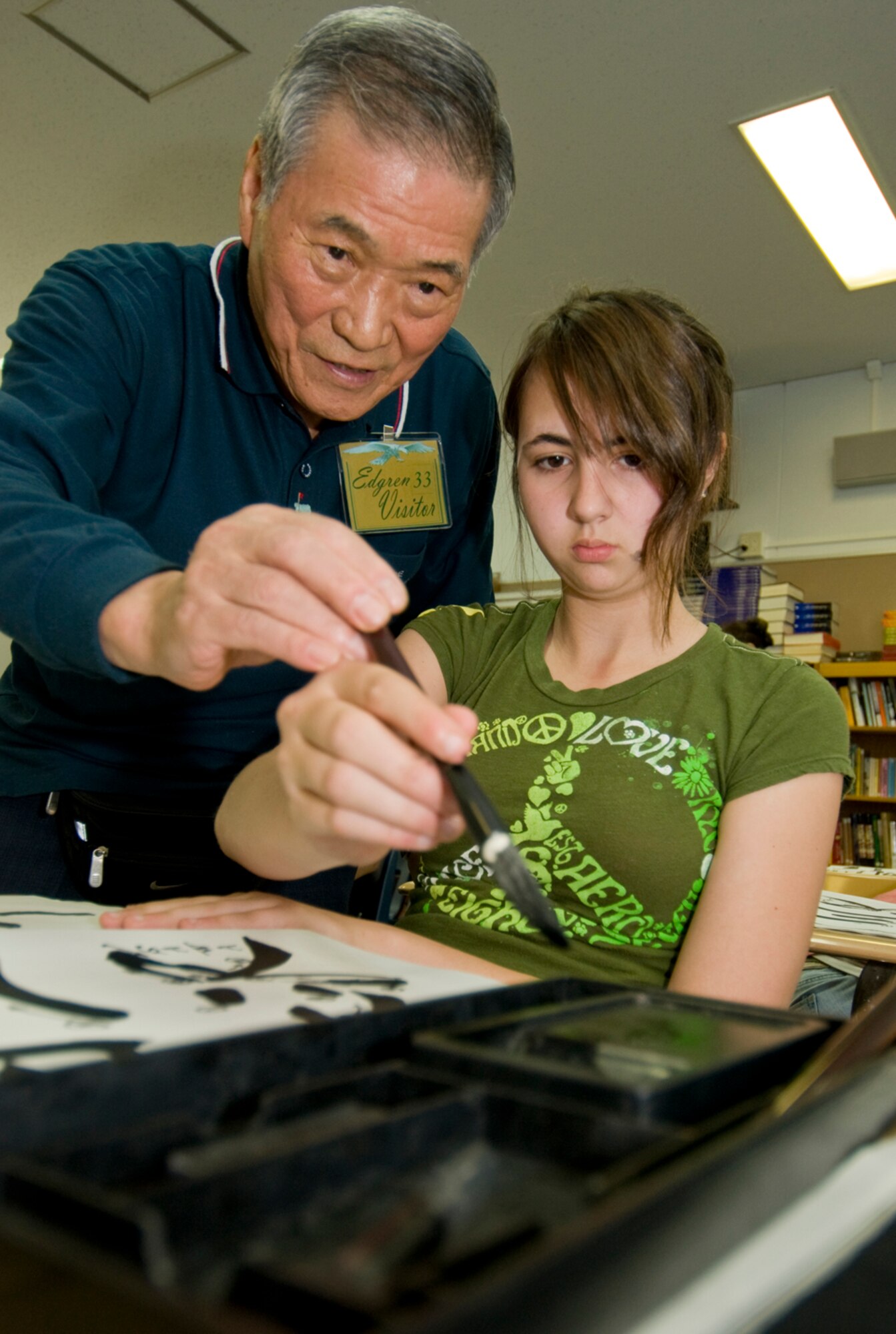 Sensei Koki Takahachi teaches Paige Powell-Griffin, daughter of Master Sgt. Stephen Griffin, how to apply ink onto a calligraphy brush, during a shodo calligraphy lesson at an Edgren High School Intercultural Education class June 3. Mr. Takahachi taught students the basic steps of Japanese calligraphy, which not only communicates but also serves as an art form. (U.S Air Force photo/ Senior Airman Jessica Lockoski) 