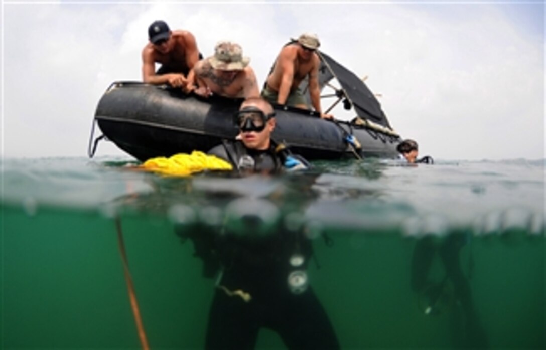 U.S. Navy sailors from Mobile Diving and Salvage Unit 1 check the manifold of Petty Officer 2nd Class Brody Dorton’s (center) scuba tanks before his dive during a Joint POW/MIA Personnel Accounting Command recovery mission in Quynh Phuong, Vietnam, on May 30, 2010.  The mission of Joint Personnel Accounting Command is to achieve the fullest possible accounting of all Americans missing as a result of the nation's past conflicts.  
