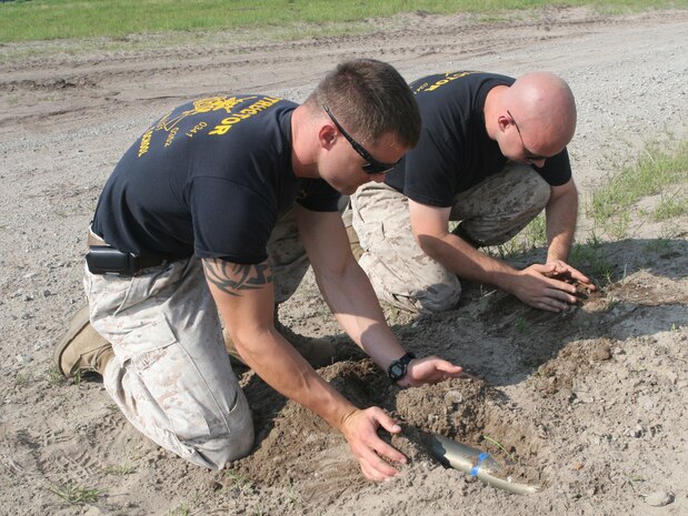 Sgt. Marcus D. Jeansonne (left) and Cpl. Joseph A. Lyons (right) the Convoy Leaders course instructors hide a simulated improvise explosive device during the Convoy Leaders Course that took place at the Battle Skills Training School June 9, 2010, aboard Camp Lejeune, NC. The instructors are required to have combat experience so they can make the exercise realistic so the students can practice for real situations during deployments.