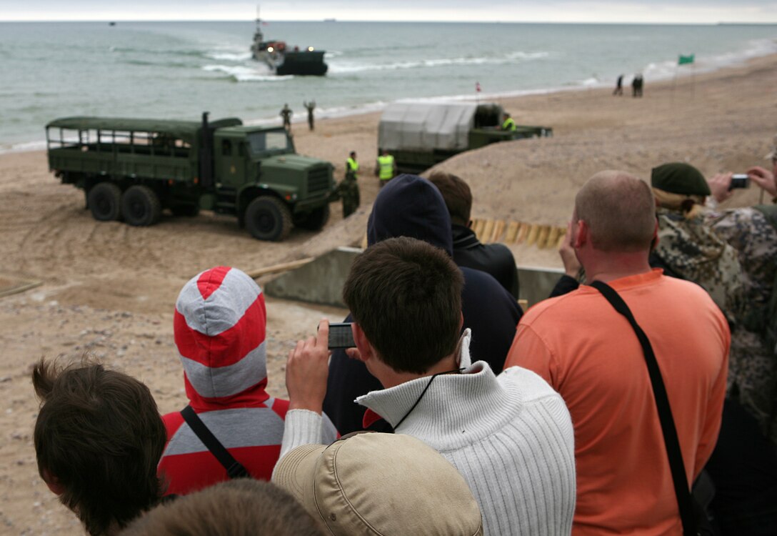 Local Latvian citizens and members of the National Armed Forces of Latvia observe a beach landing where Marines and Sailors participating in exercise BALTIC OPERATIONS 2010 conduct a maritime preposition force (MPF) offload of vehicles and equipment. The MPF offload portion is one of largest portions of exercise BALTOPS, a multinational maritime exercise designed to increase interoperability between the 12 participating nations and increase maritime safety and security.