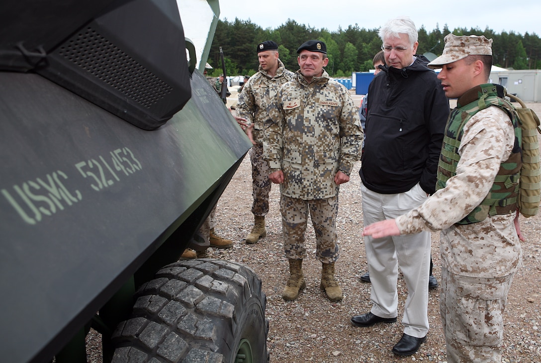 Lance Cpl. Noah Peczeli (right), a light armored reconnaissance vehicle (LAV) mechanic with 4th Landing Support Battalion, explains the mechanical capabilities of the engine in the LAV to the Latvian Minister of Defense Imants Liegis (center), and Maj. Gen. Juris Maklakovs (left), the Commander of National Armed Forces of Latvia. The Minister of Defense and Chief of Defense visited several sights in the Ventspils area where U.S. and Latvian forces are working together to conduct a maritime preposition offload exercise.