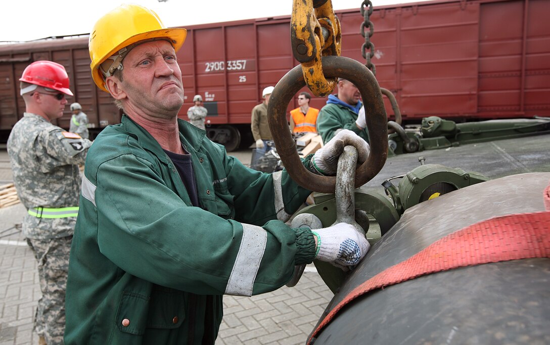 A civilian railway engineer attaches a hoist cable to an M1A1 Main Battle Tank during the rail-way movement portion of the maritime preposition force (MPF) offload portion of exercise BALTIC OPERATIONS 2010. The MPF offload portion is one of largest portions of exercise BALTOPS, a multinational maritime exercise designed to increase interoperability between the 12 participating nations and increase maritime safety and security.