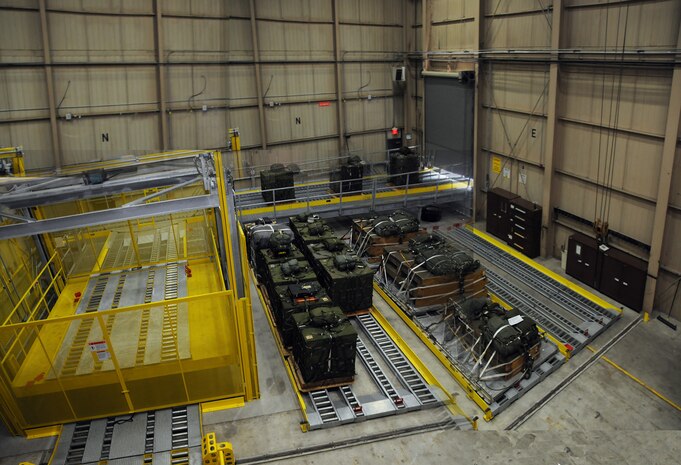 Stage four: After rigging and repair is complete, bundles are pushed through another set of sliding doors and are stored in this holding section. The section is equipped with a yellow cargo elevator to raise the bundles onto the final platform for placement onto cargo loading vehicles. Including the main processing section, the total storage space in the facility will hold more than 60 bundles, compared to the previous system which held 16 to 20. (U.S. Air Force photo illustration/Staff Sgt. Daniel Bowles)