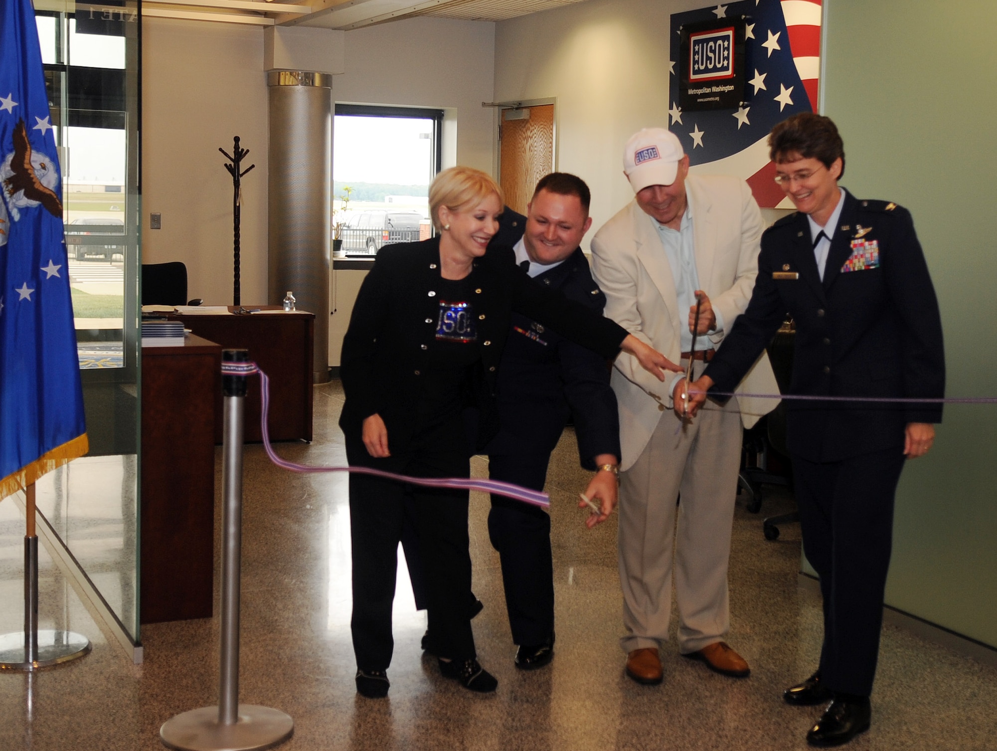 JOINT BASE ANDREWS, MD.-Colonel Jacqueline Van Ovost, 89 AW commander, (right), Ms. Elaine B. Rogers (left), USO of metropolitan Washington president, and Mr. John Marselle (center), chairman of the board for the USO, cut the ribbon for the opening ceremonies at the passenger terminal here on June 9, 2010. The USO has been located inside the passenger terminal since 1995. Its volunteers have assisted 1,154 military and families members so far in 2010. (U.S. Air Force photo by Senior Airman Melissa V. Brownstein)