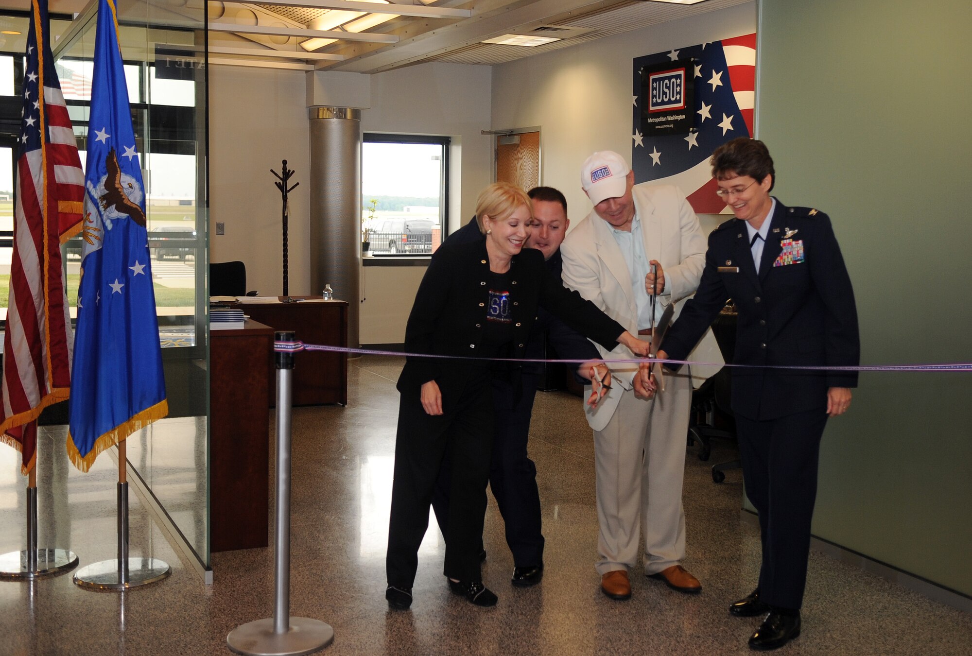 JOINT BASE ANDREWS, MD.-Colonel Jacqueline Van Ovost, 89 AW commander, Ms. Elaine B. Rogers (left), USO of metropolitan Washington president, and Mr. John Marselle (center), chairman of the board for the USO, cut the ribbon for the opening ceremonies at the passenger terminal here on 9 June 2010. The USO has been located inside the passenger terminal since 1995. Its volunteers have assisted 1154 military and families members so far in 2010. (U.S. Air Force photo by Senior Airman Melissa V. Brownstein)