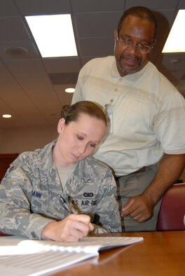 Carl Cameron, 43rd Airlift Wing, legal office, assists Airman 1st Class Erika Spann (left), 43rd Security Forces Squadron as she signs legal documents in the Pope courtroom, June 6. Mr. Cameron began working in Pope’s legal office June 2006. (U.S. Air Force Photo/1st Lt. Cammie Quinn) 