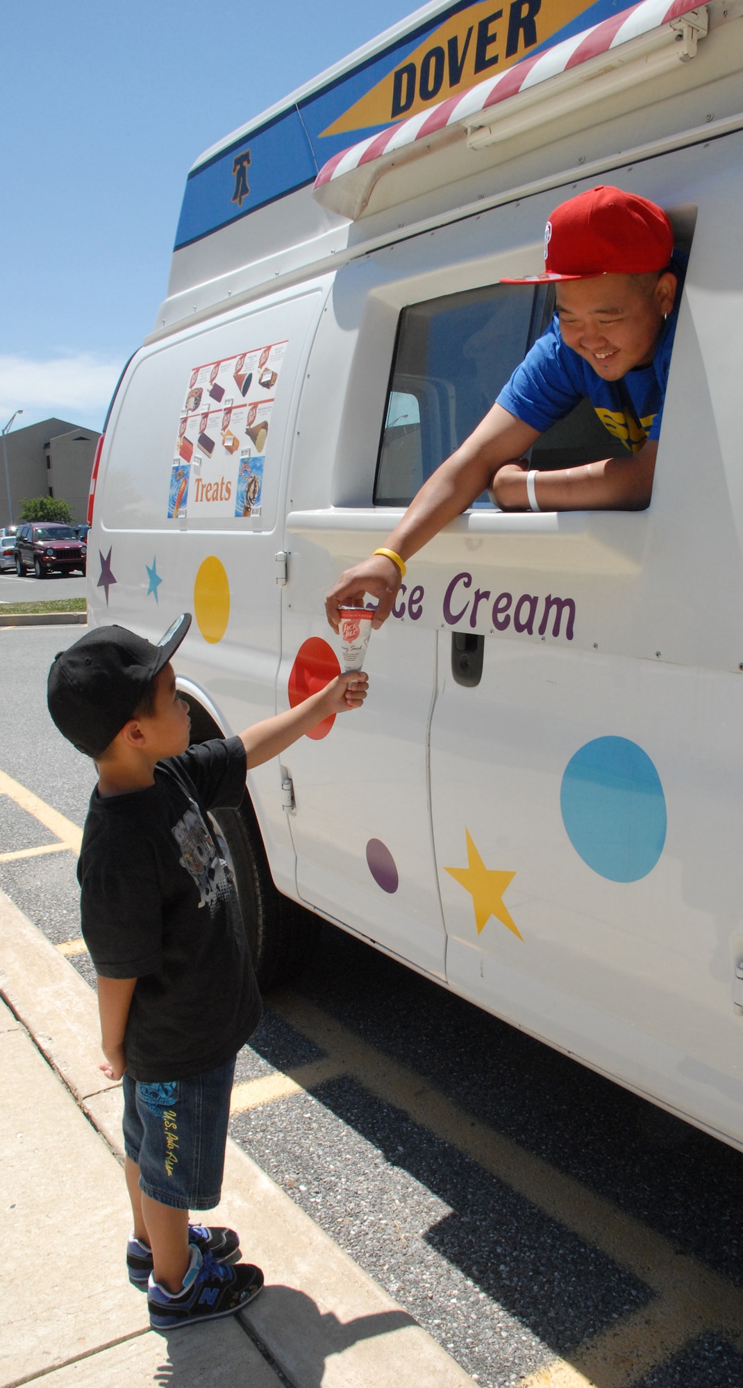 (Right) Edison Malaga, 436th Force Support Squadron Eagle Lanes Bowling Center Ice Cream Man, hands his son, Zane, an ice cream cone. The ice cream truck is driving around base and housing area from 12 ? 8 p.m. offering flavors of orange cream, vanilla, fudge and chocolate chip sandwiches. (U.S Air Force photo/ Airman 1st Class Shen-Chia Chu)