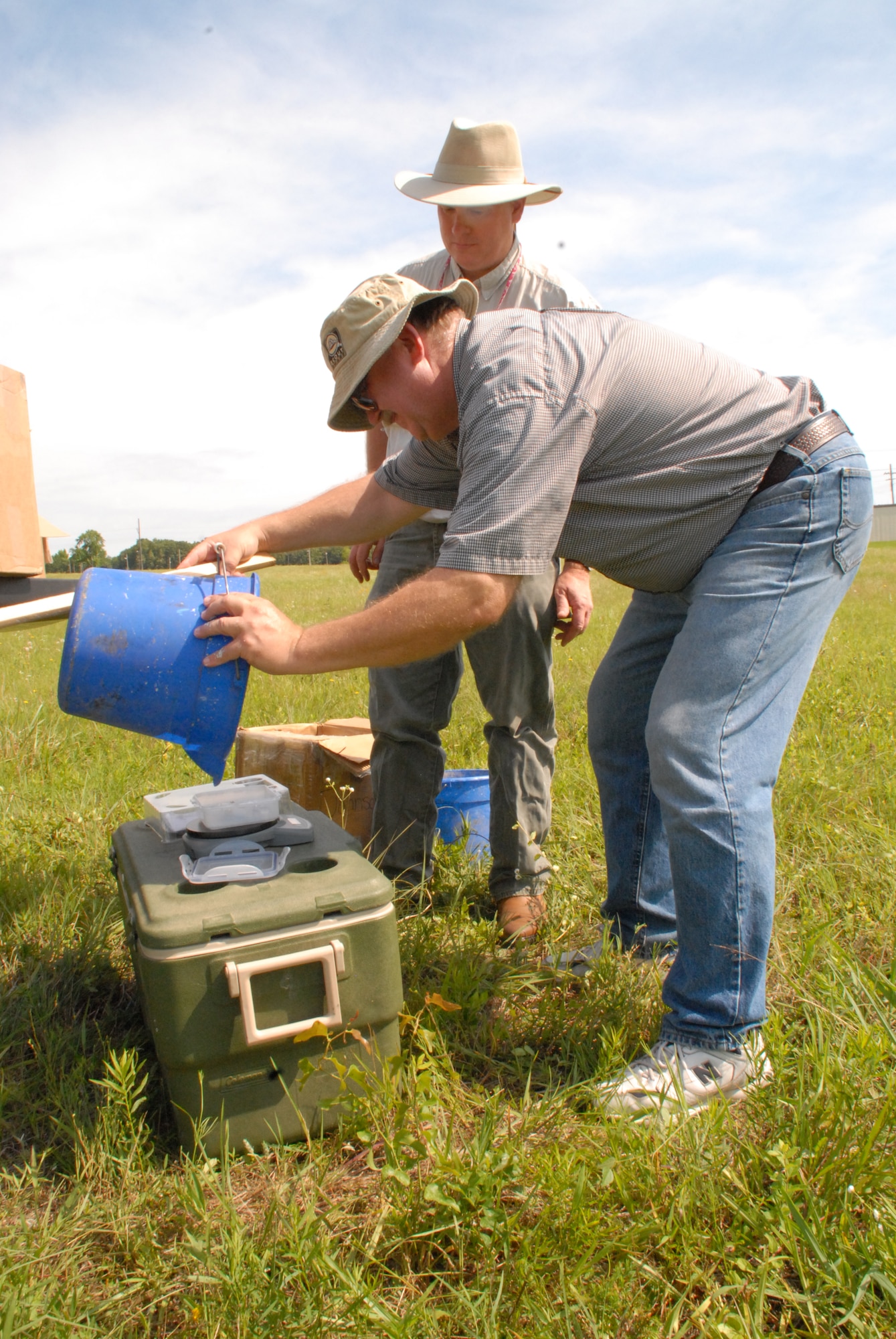 Dr. Kelly Loftin (background) and Dr. John Hopkins of the University of Arkansas Division of Agriculture collect red imported fire ants on base June 7 as part of a bi-annual study to control the non-native fire ant population. (U.S. Air Force photo by Capt. Joe Knable)
