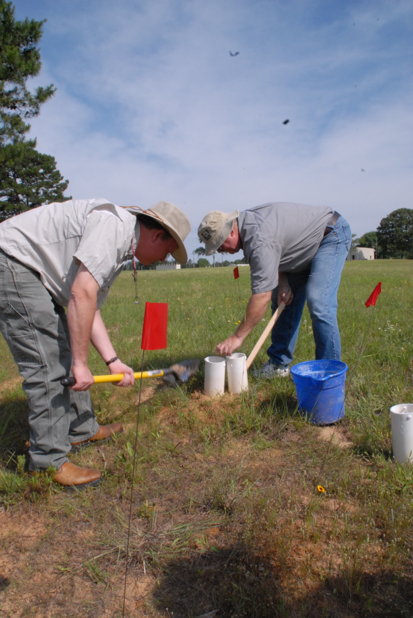 Dr. Kelly Loftin (left) of the University of Arkansas Division of Agriculture disturbs an red imported fire ant hill while Dr. John Hopkins collects ants on base June 7 as part of a bi-annual study to control the non-native fire ant population. (U.S. Air Force photo by Capt. Joe Knable)