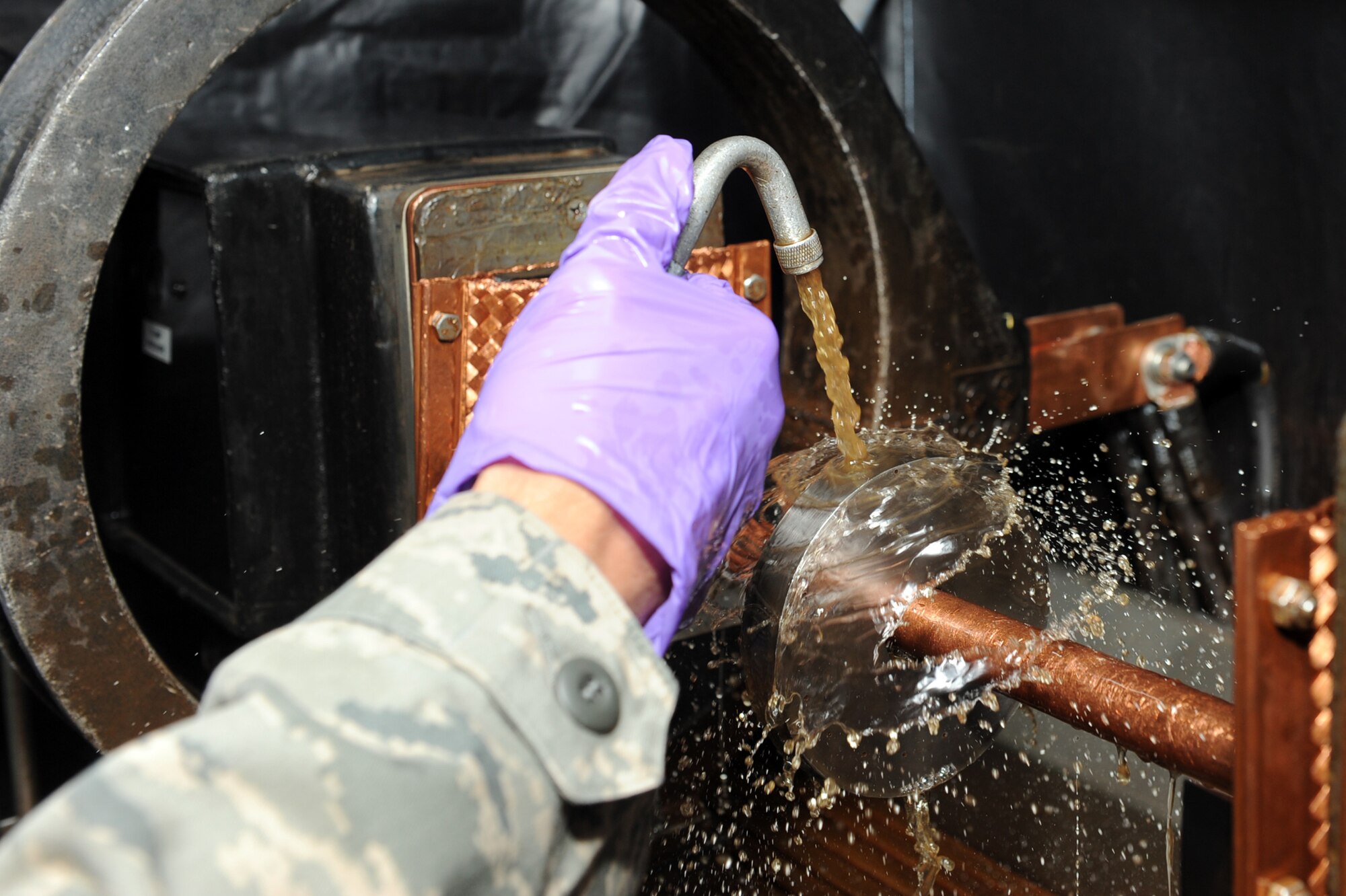 Airman 1st Class Quinten Roehm, 19th Equipment Maintenance Squadron non-destructive inspection apprentice, sprays a magnetic particle solution June 8 on a ketos ring while magnetizing it during a magnetic particle inspection at the base non-destructive inspection lab. The ketos ring is used to run a systems check on the performance of the magnetic particle inspection system. (U.S. Air Force photo by Senior Airman Ethan Morgan)