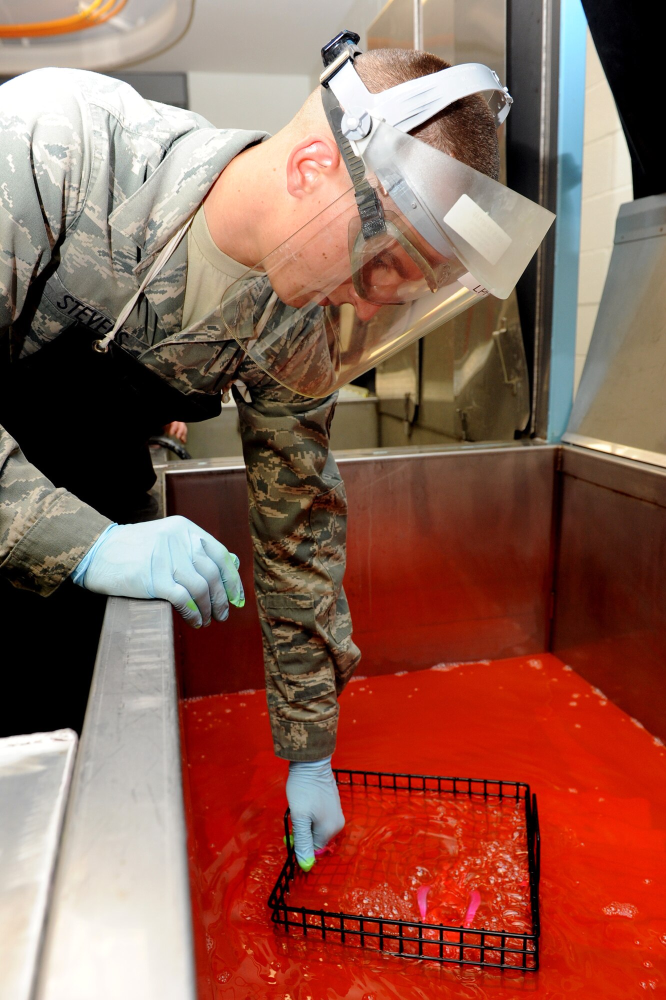 Airman 1st Class John Stevens, 19th Equipment Maintenance Squadron non-destructive inspection journeyman, dips a tow fitting arm into a remover emulsifier June 4 during a fluorescent liquid penetrant inspection. The remover emulsifier is used to remove any excess fluorescent liquid penetrant that may have not been removed in the first initial wash. (U.S. Air Force photo by Senior Airman Ethan Morgan)