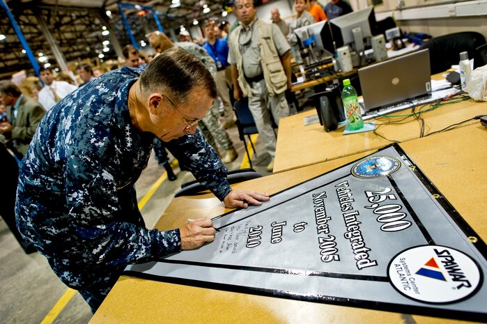Navy Adm. Mike Mullen, chairman of the Joint Chiefs of Staff, signs a pennant signifying the completion of 25,000 electronic systems vehicle integrations at Naval Weapons Station Charleston, S.C., June 3, 2010. (DoD photo by Mass Communication Specialist Chad J. McNeeley)