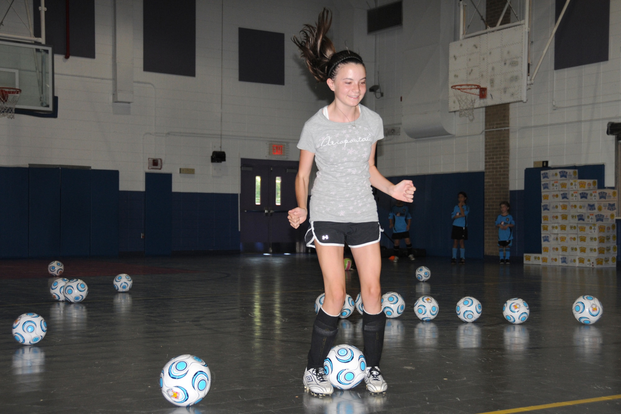 Shelby McElroy, 15, does a hop drill during the first day of the Challenger Sports British Soccer Camp at the youth center gym Monday.  The camp for ages 4-18 had to be moved inside because of “black flag” weather conditions.  Shelby's parents are 1st Lt. Angela and James McElroy, 81st Medical Operations Squadron.  (U.S. Air Force photo by Kemberly Groue)