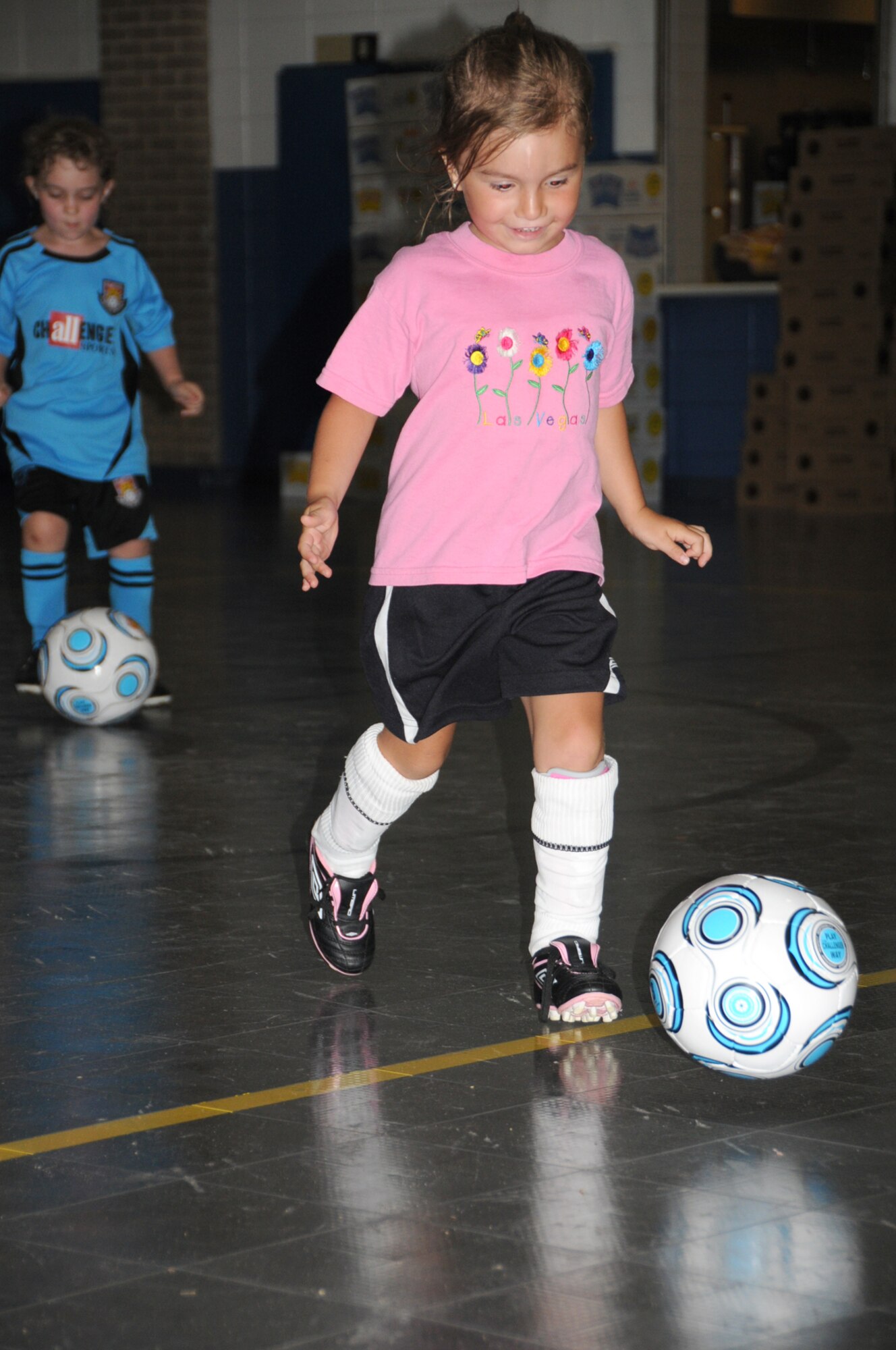 5-year-old Kadyn McElroy kicks a soccer ball down the court.   The camp had to be moved inside Monday because of “black flag” weather conditions.  Kadyn’s parents are 1st Lt. Angela and James McElroy, 81st Medical Operations Squadron.   (U.S. Air Force photo by Kemberly Groue)