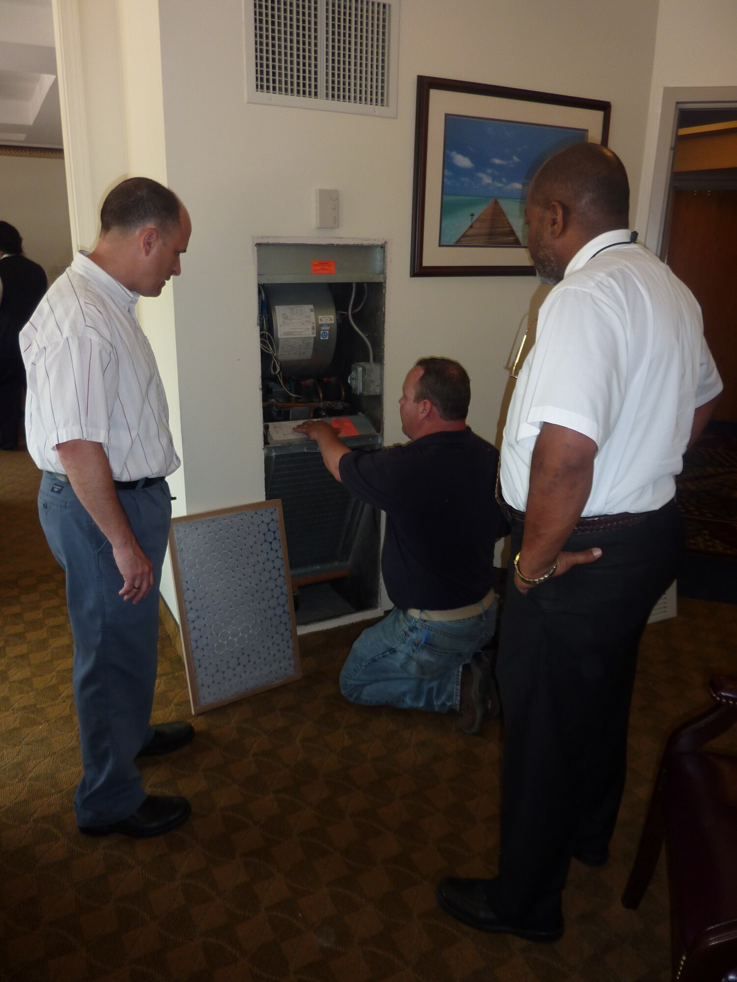 Mr. Barcomb, left, and lodging operations manager Bob Jones look on as evaluator Tom Rafferty explains ways to reduce the base’s energy consumption.  (U.S. Air Force photo by Scott Lawless)