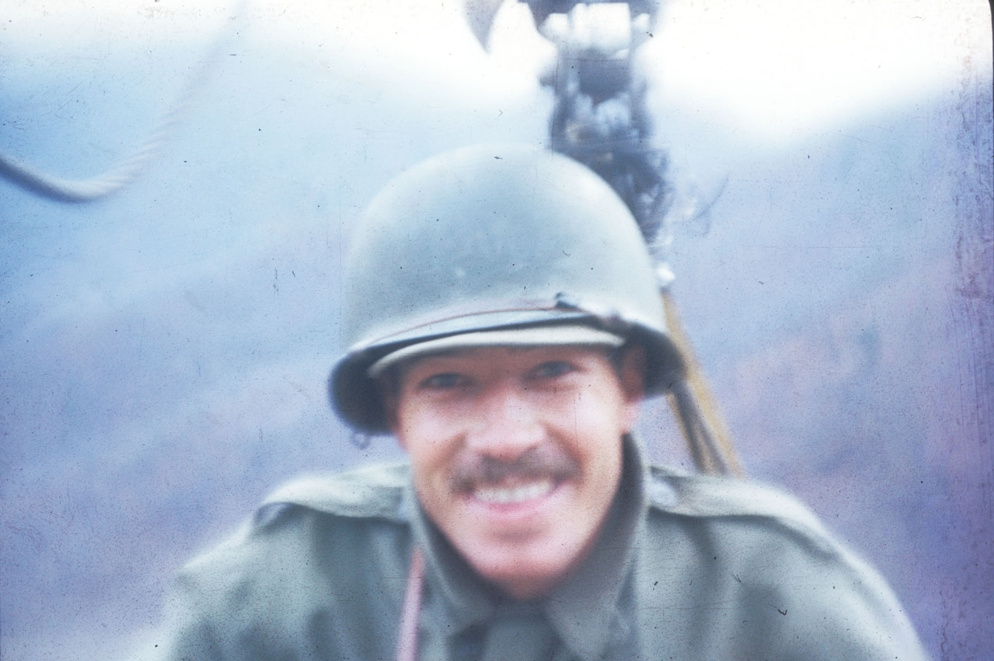 The smile on this TACP member belies the fact that he is dangling in mid-air on a 1/2-mile-long cable car wire, exposed to enemy artillery fire. It was the only practical way to reach a certain peak to control an airstrike. (U.S. Air Force photo)