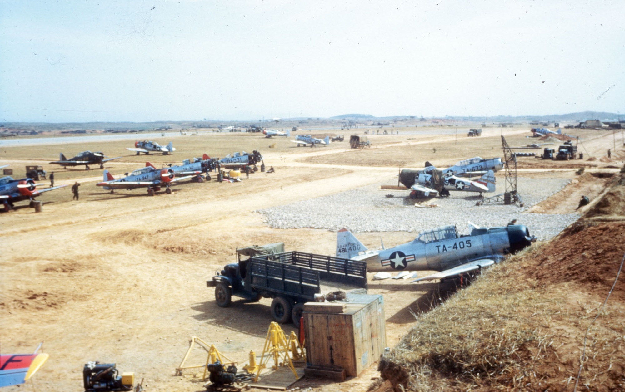 Mosquitos at K-6 (Pyongtaek) in the spring of 1951. The maintenance “shop” is the open-air gravel pad on the right of the photo. The taxiways are dirt and the PSP (pierced steel planking) runway is in the background on the left. (U.S. Air Force photo)